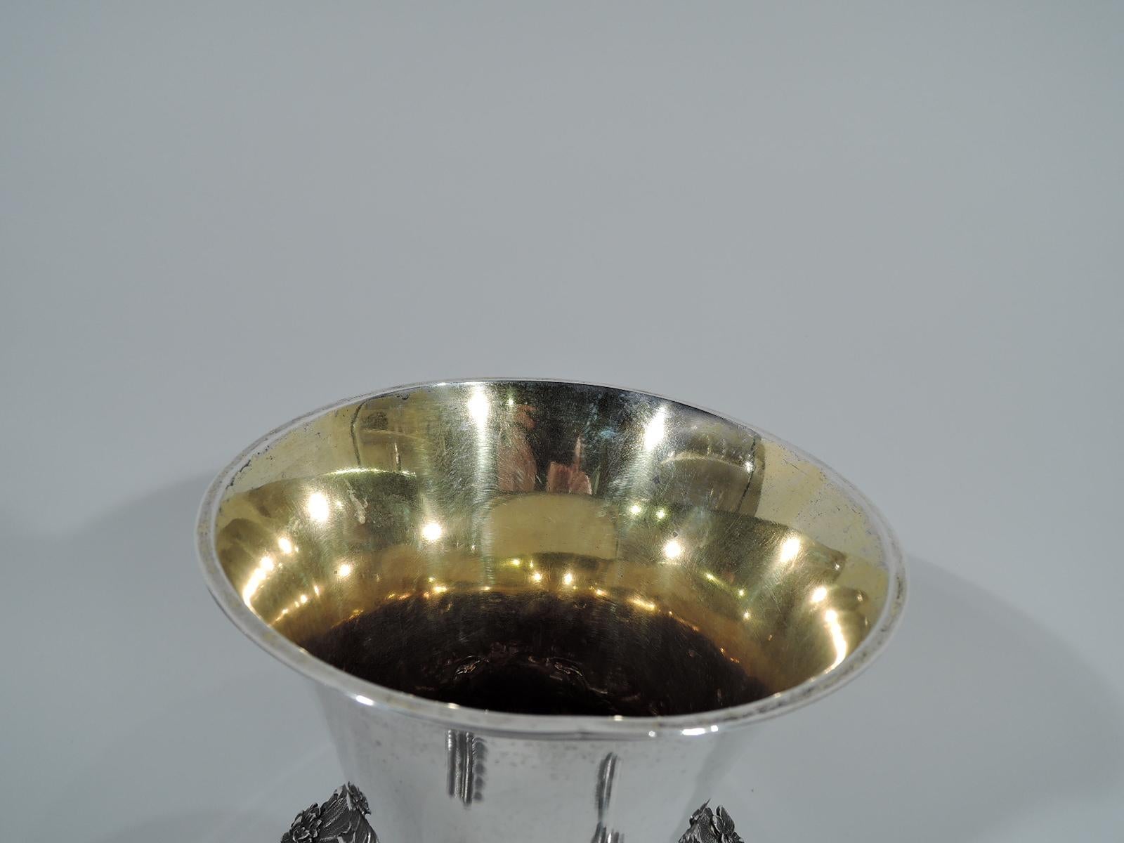 Indian Colonial silver chalice with chased and stippled leaves and flowers. Bellied bowl with flared rim, leaf flange and raised foot. Bowl decorated with leaves and flowers alternating with flutes. Foot decorated with leaves. Gilt interior. A