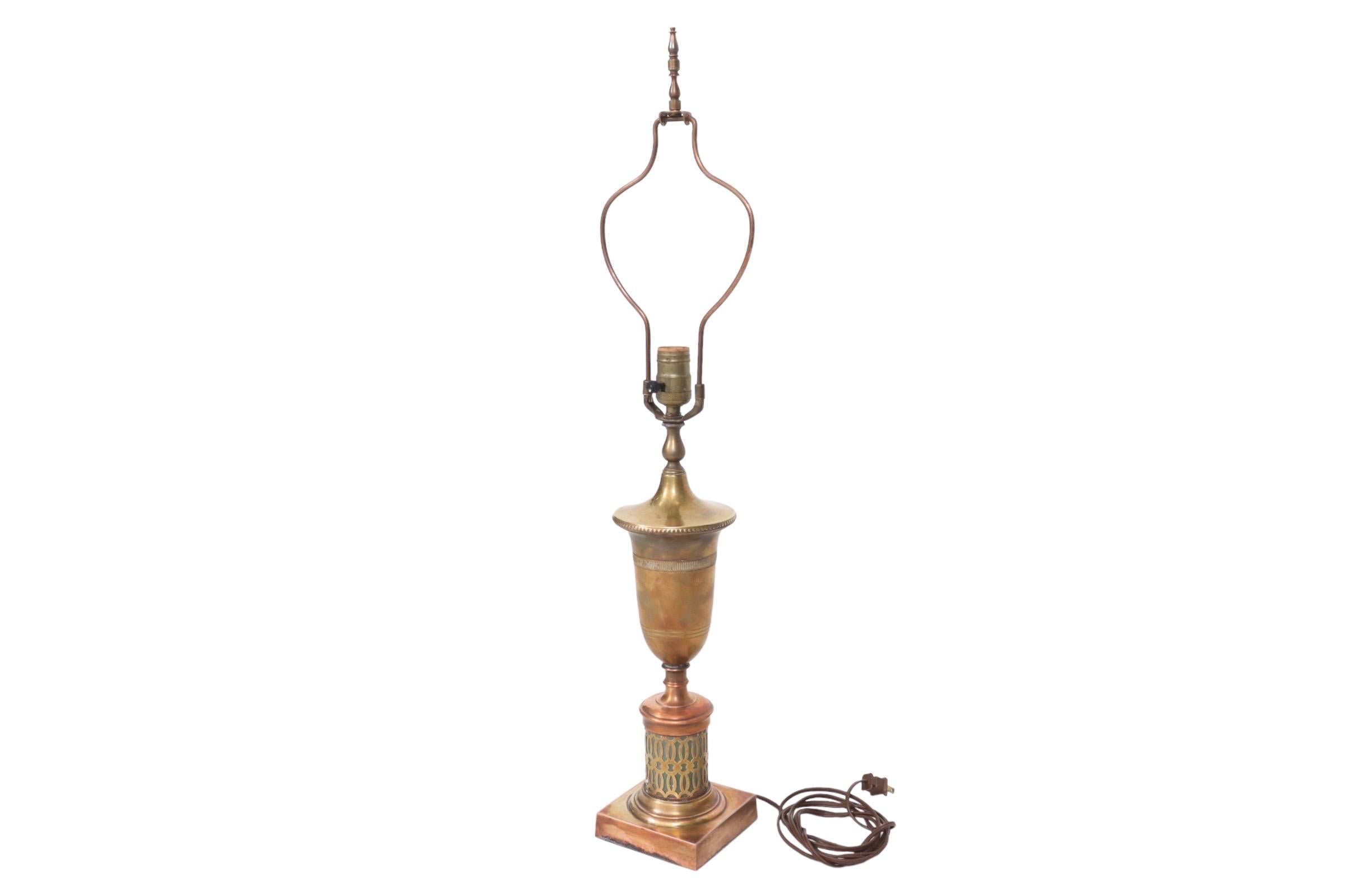 An Indian style table lamp made of copper and brass. An unusual baluster shaped harp has a tall turned finial, above a simply decorated brass vase. Below, is a teal base inside a pierced copper lattice with a square foot. Measures 4.75