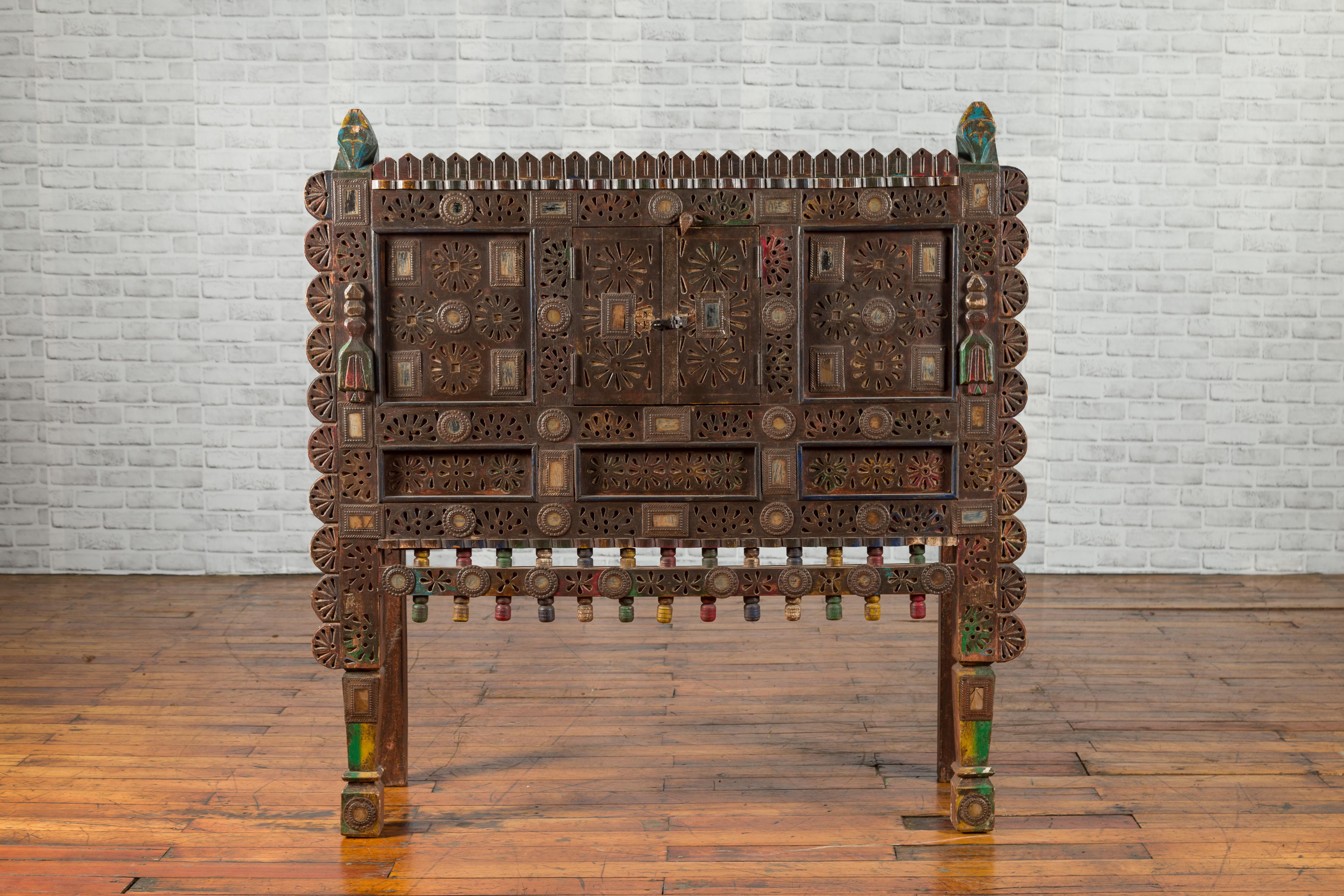 An antique Indian Damachiya shesham wood polychrome bridal cabinet from the early 20th century, with pierced geometric patterns, semi-circular motifs, inlaid mirrors and carved stylized horse heads. Created in Western India to store bridal dowries,