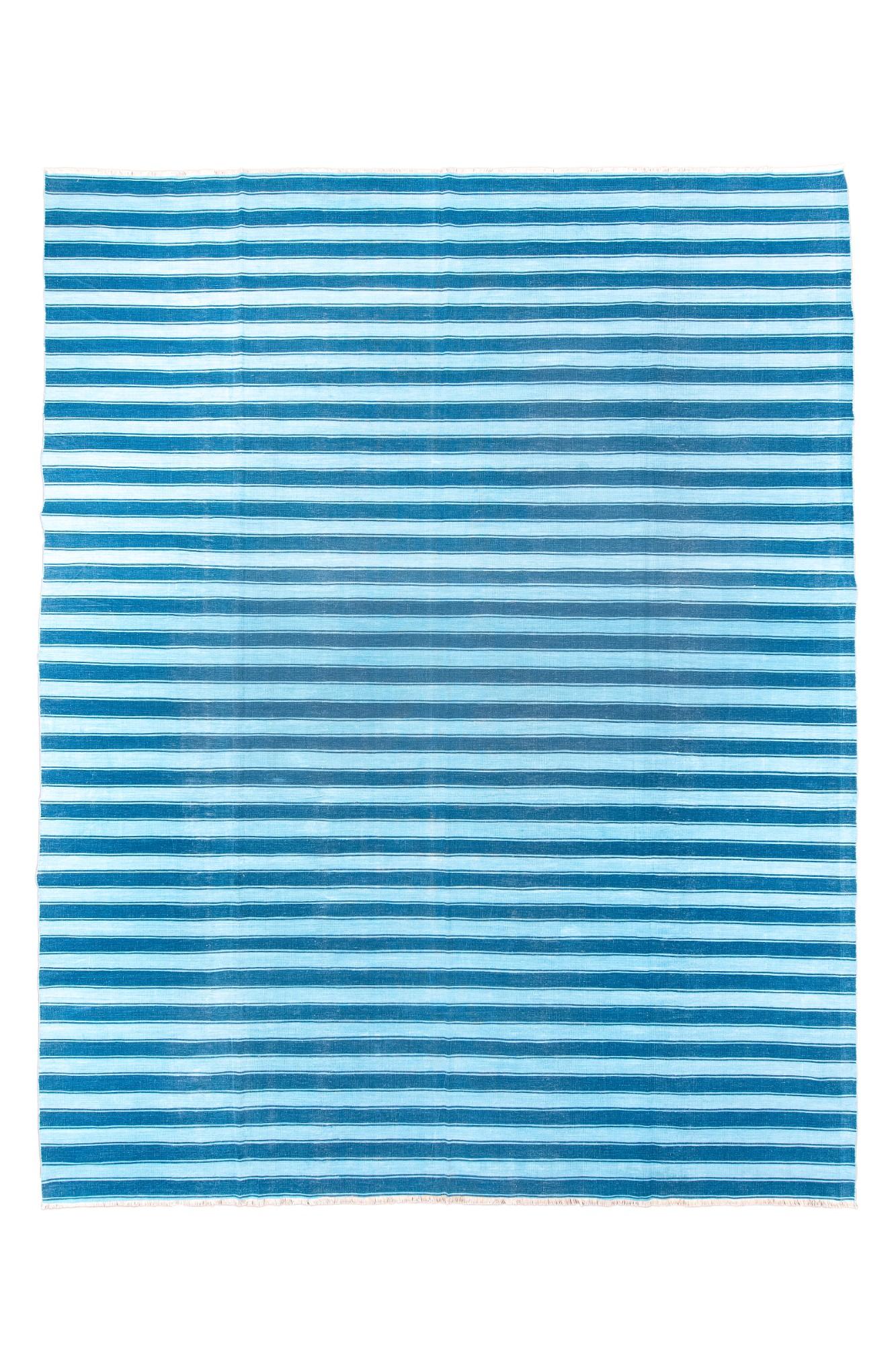 Ce tissu plat en coton réglable dans toutes les directions présente un motif de rayures égales bitonales dans les tons bleu foncé et blanc cassé. Les transitions de couleurs sont facilitées par les lignes fines adjacentes aux bandes plus