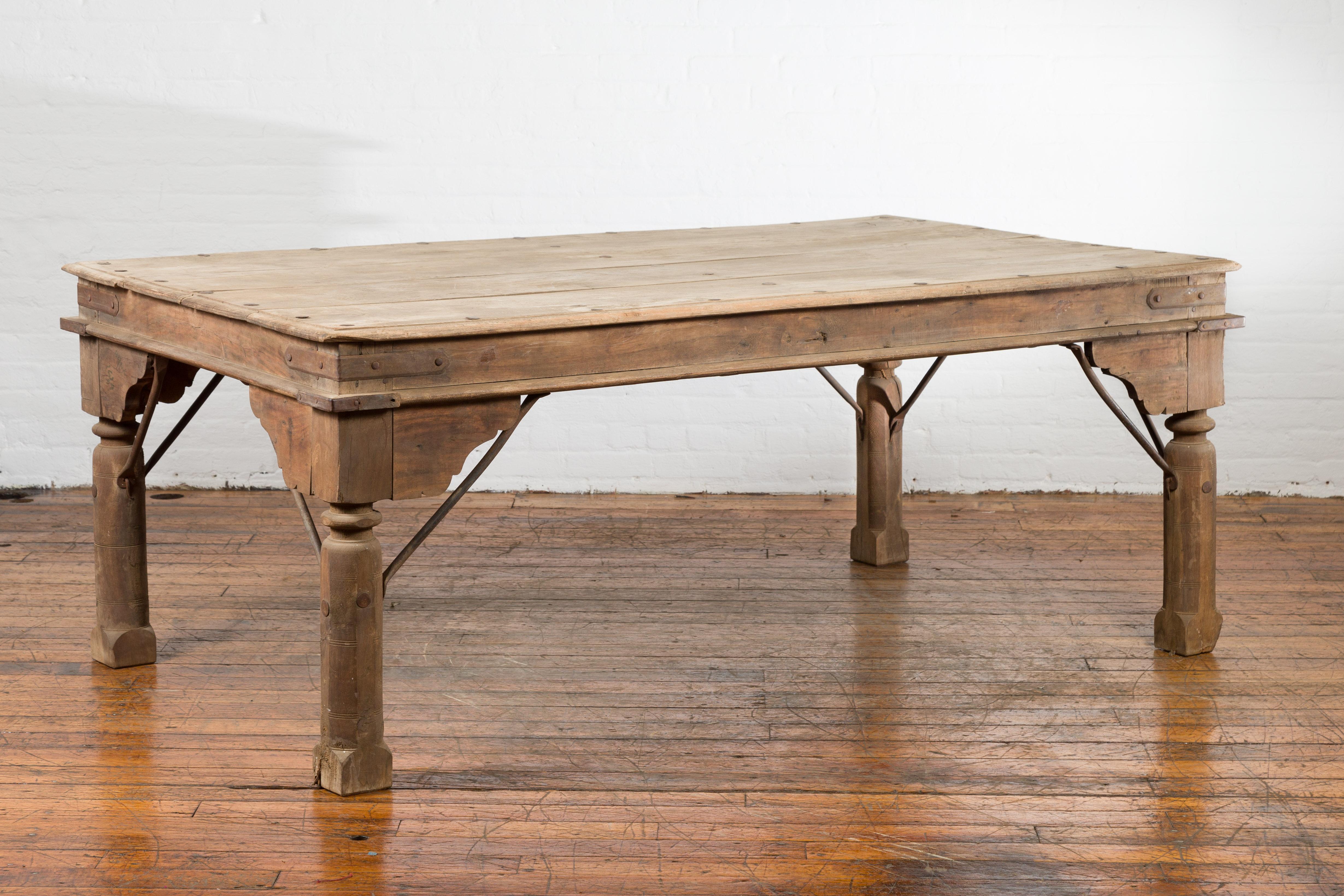 A large antique rustic Indian dining table from the 19th century, with iron details. Created in India during the 19th century, this dining table features a rectangular planked top with iron studs, sitting above a simple apron accented with iron