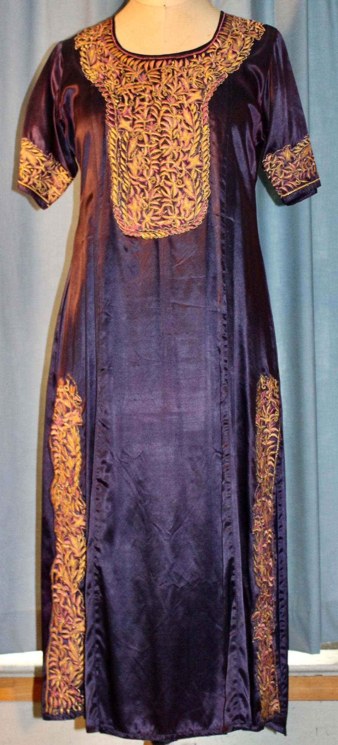 Caftan en soie violette richement brodé de fils de soie rose et or.
Fentes sur les côtés