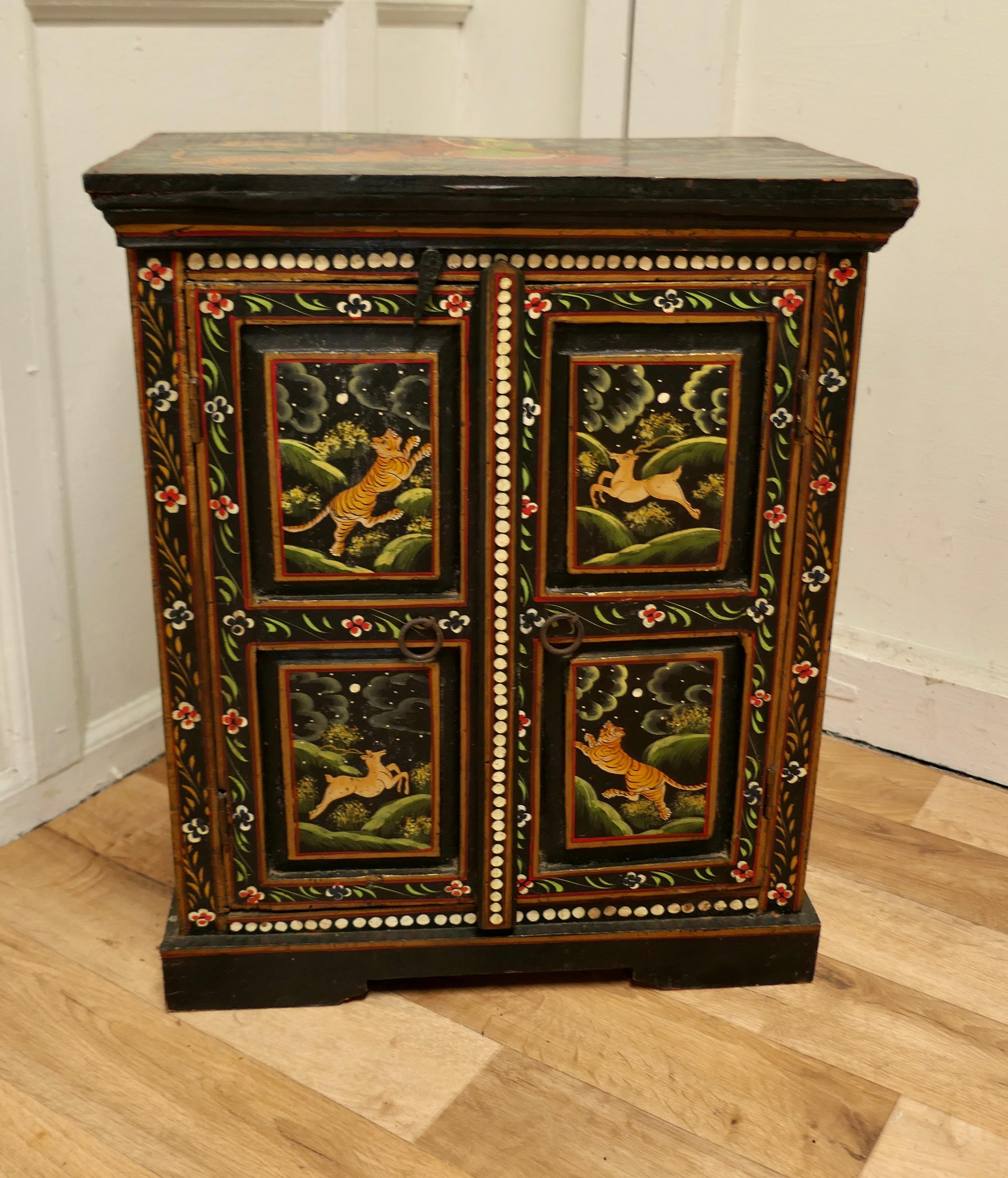 Indian folk art painted cupboard 

This is an unusual piece, the cupboard stands on a small plinth, it is painted in the detailed Indian Folk Art Style showing Immortals slaying Fearsome Tigers while flying through the air
The cupboard has 2