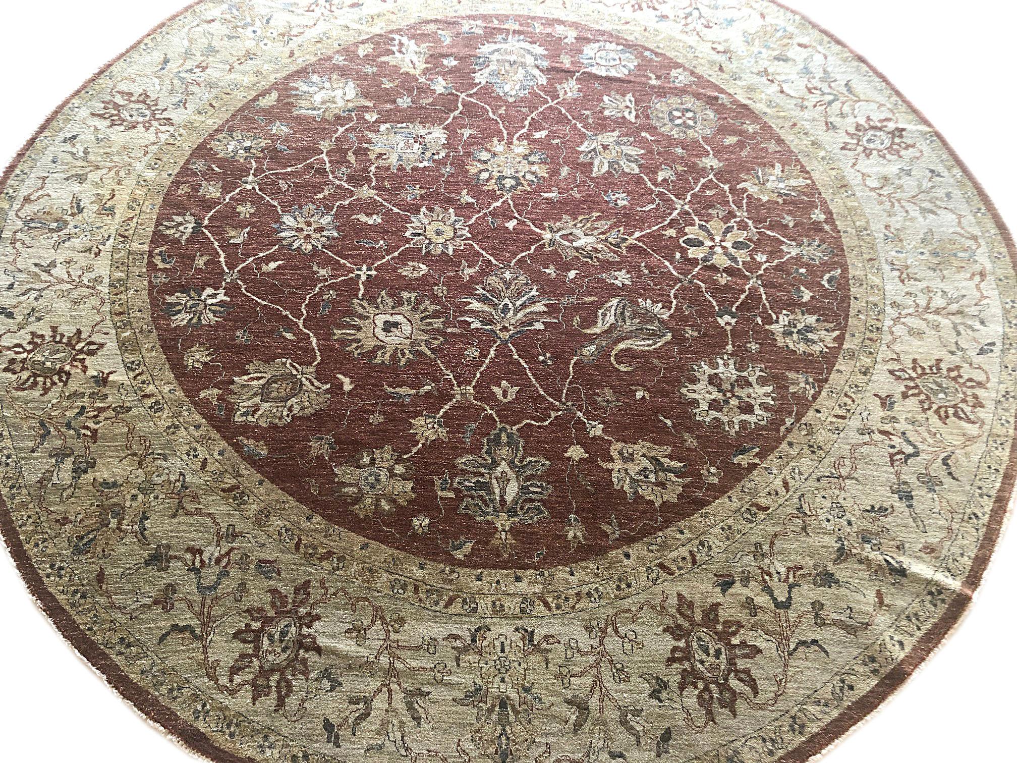 This beautiful round rug is from India and has Peshawar woven style. The size is 11 feet and 8 inches. The design is Mahal. The pile is wool and the foundation is cotton. This rug has a very small re-weaving on one side. This is a pre-owned rug.