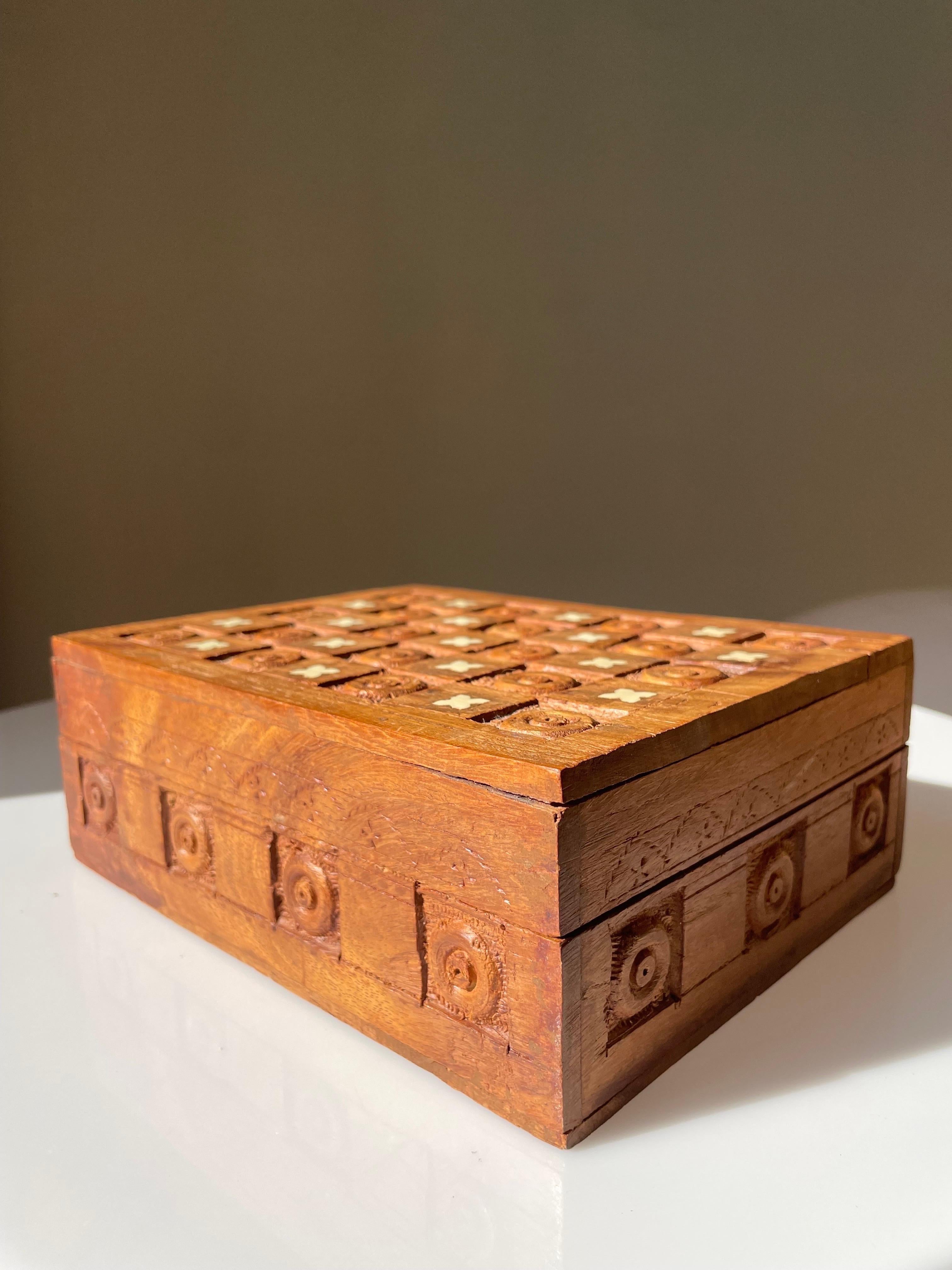 Handcarved wooden trinket box with carved geometric shapes, small handmade ornamental indentations and cream white decor on the lid. Rustic organic style. Beautiful vintage condition. 
India, circa 1970s. 