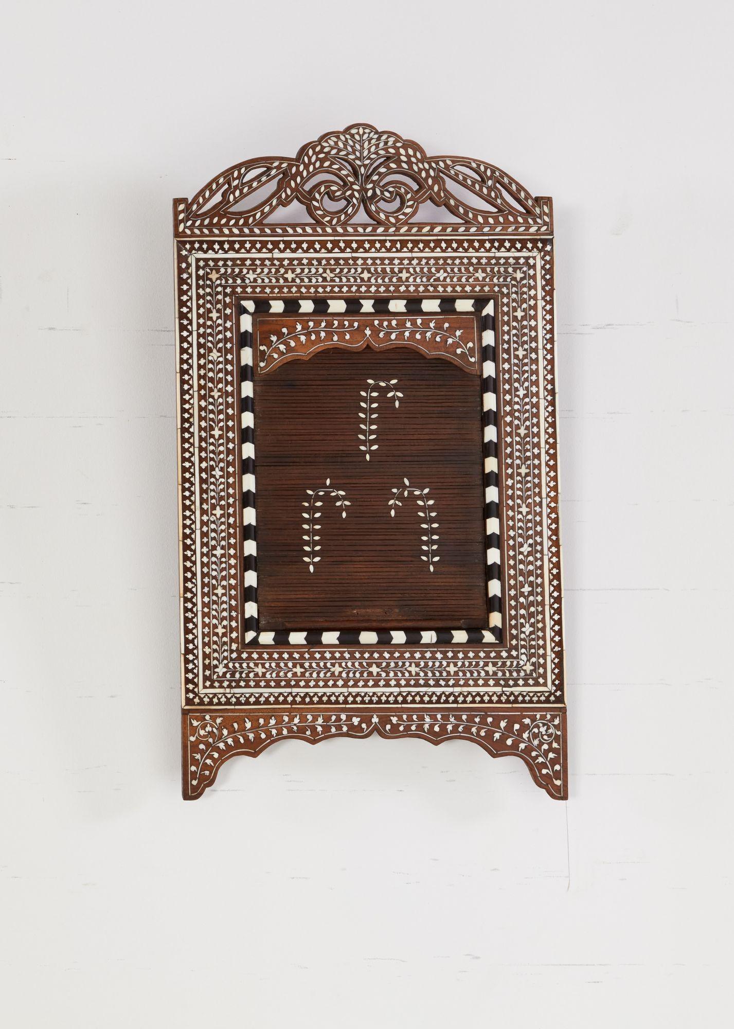 Specchio in legno di sandalo finemente intarsiato con dettagli elaborati in osso ed ebano sul piano traforato, lati profondi e smerlati e base ad arco. Specchio originale all'interno di una cornice chevron bianca e nera, con un'anta tamburellante