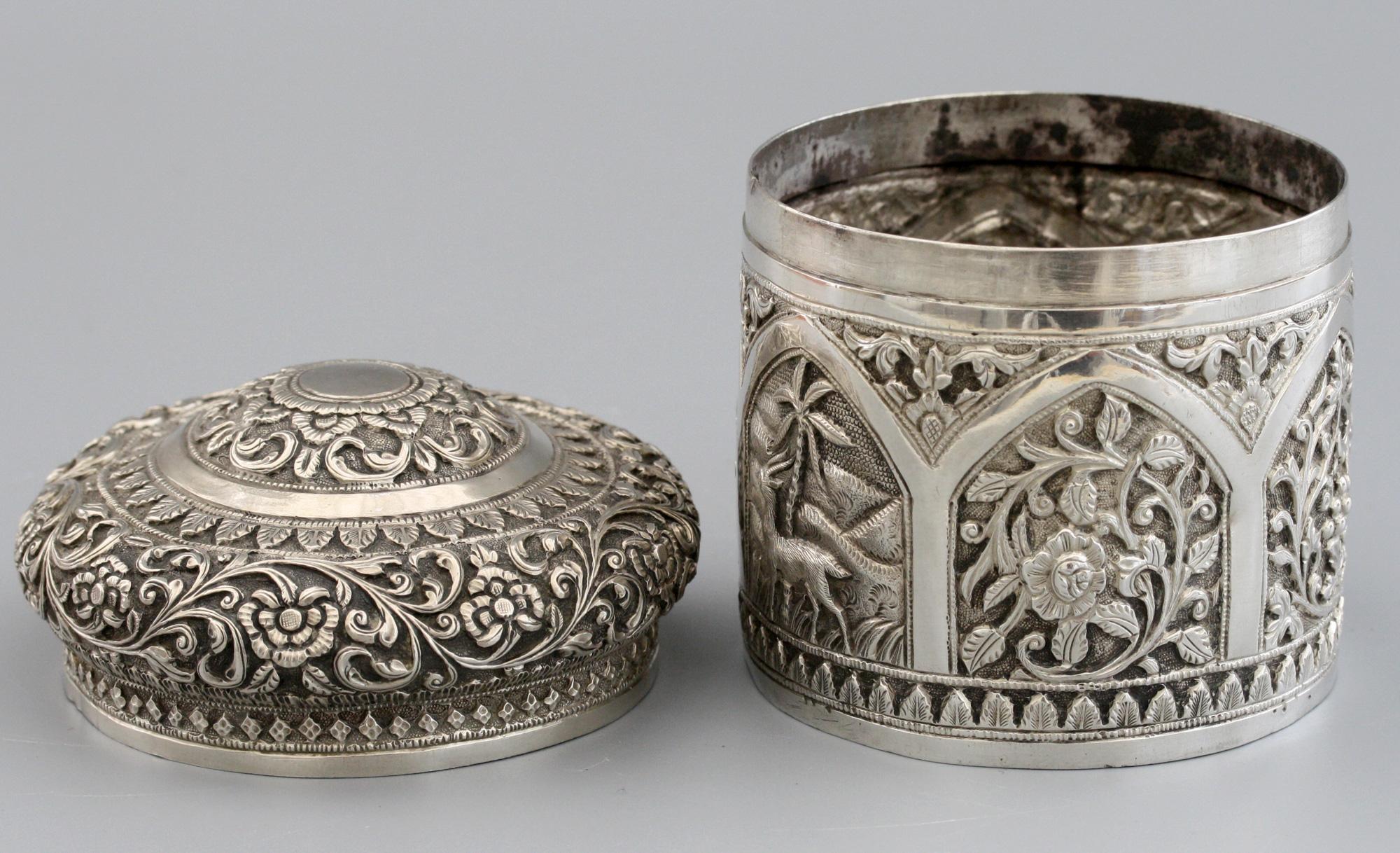 A stunning antique Indian silver lidded tea caddy decorated with ornate panels, scroll and floral designs by J Mankrai of Karachi and dating from circa 1880. This finely made tea caddy has a cylindrical shaped body with six domed relief decorated