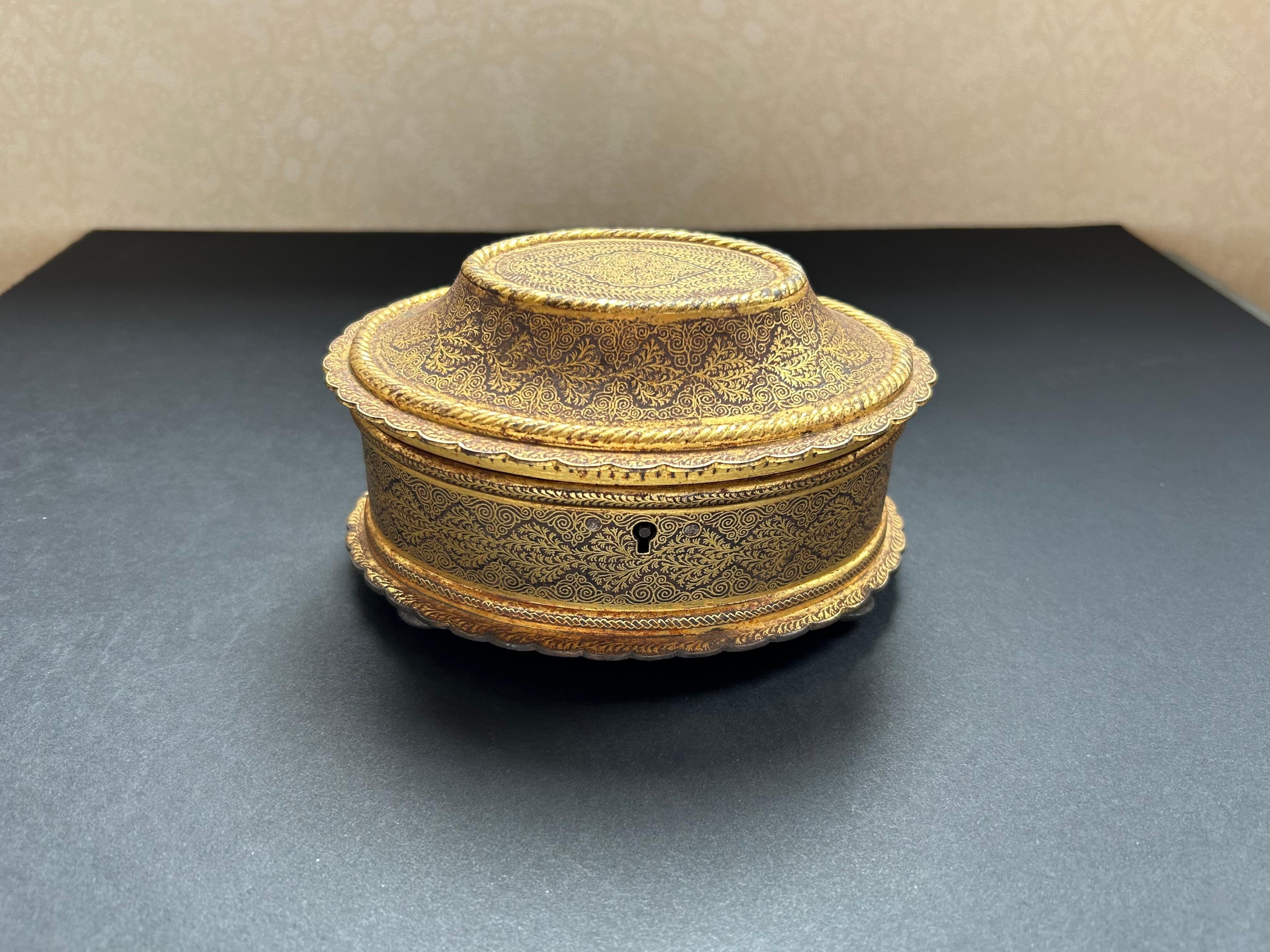 Eine exquisite indische Koftgari-Arbeitsbox oder Schmuckschatulle, um 1900, in ovaler Form. Mit sehr feinem Goldfadendekor, drei versilberten Füßen und einem versilberten Sockel. Der Deckel lässt sich öffnen und gibt den Blick auf ein abgenutztes