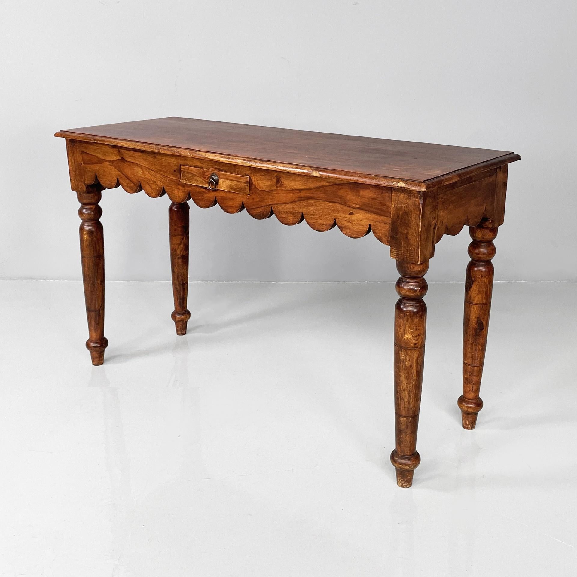 Indian mid-century modern console with drawer in wood, 1970s
Console table with rectangular top, entirely in teak wood. On the front there is a drawer with a metal handle. There is a rounded decoration on the entire profile. Turned wooden legs. It