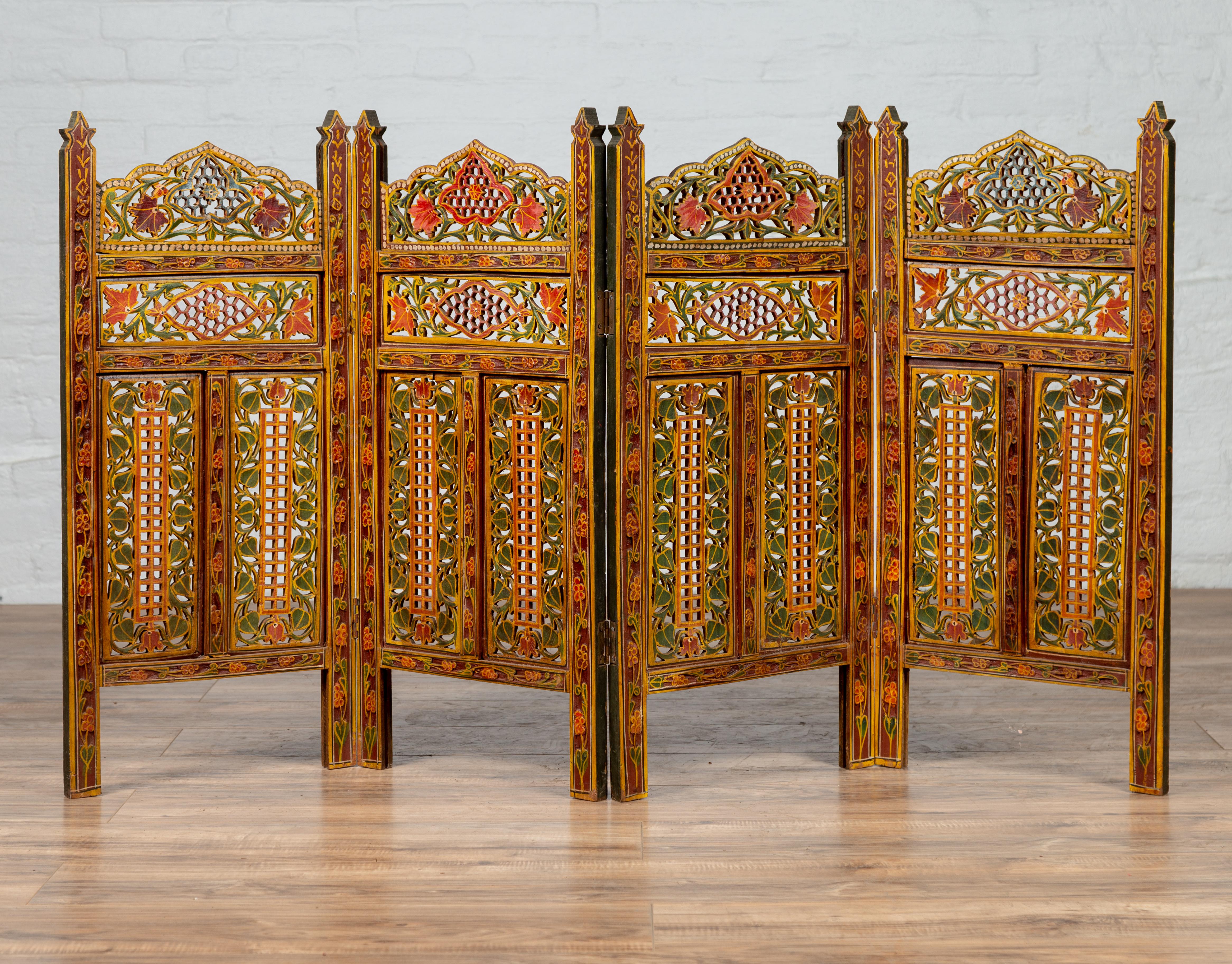 A petite Indian vintage multi-color open fretwork four-panel screen, hand carved and hand painted. Born in India during the midcentury period, this small and exquisite screen features four folding panels, each adorned with a mesmerizing décor of