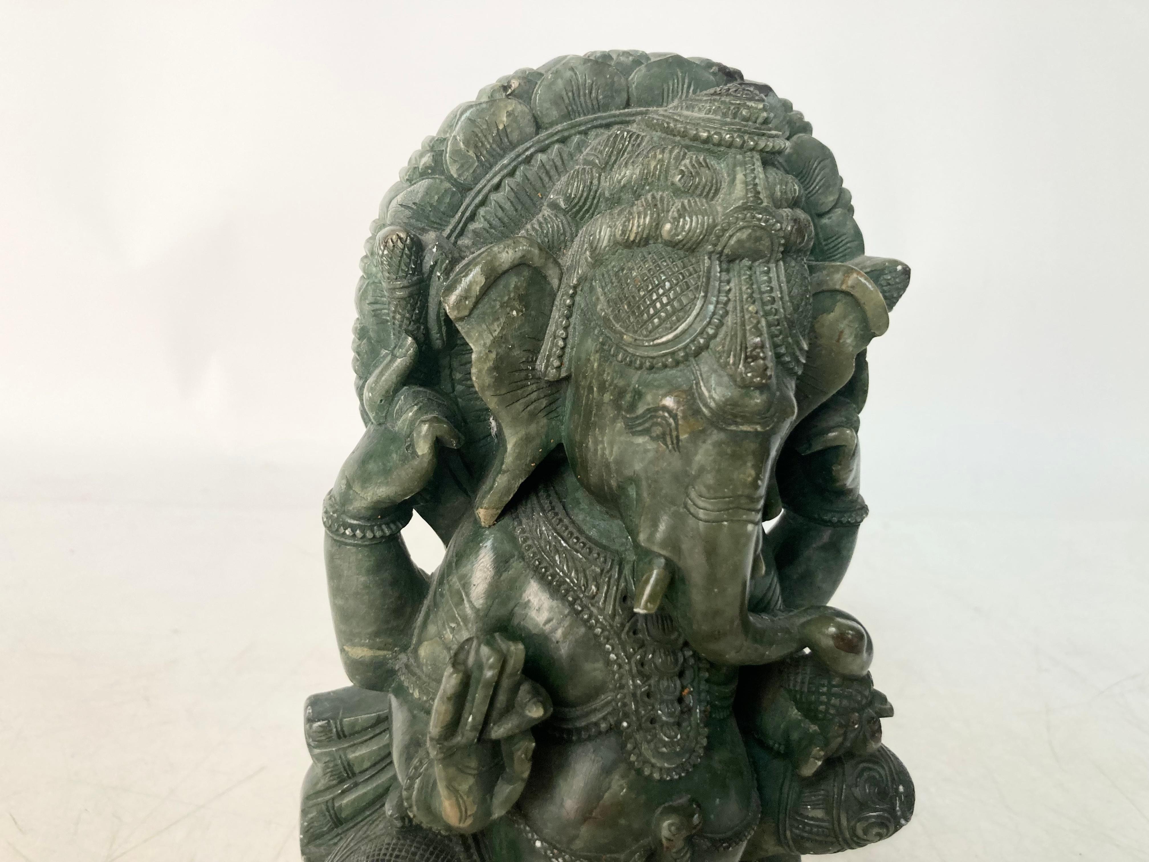 A deep Spinach Green Onyx depiction of the Indian God and destroyer of obstacles Ganesha. Traditionally seated on a Lotus throne, the figure is intricately dressed with elaborate headdress, breastplate and bracelets on his four arms and ankles.