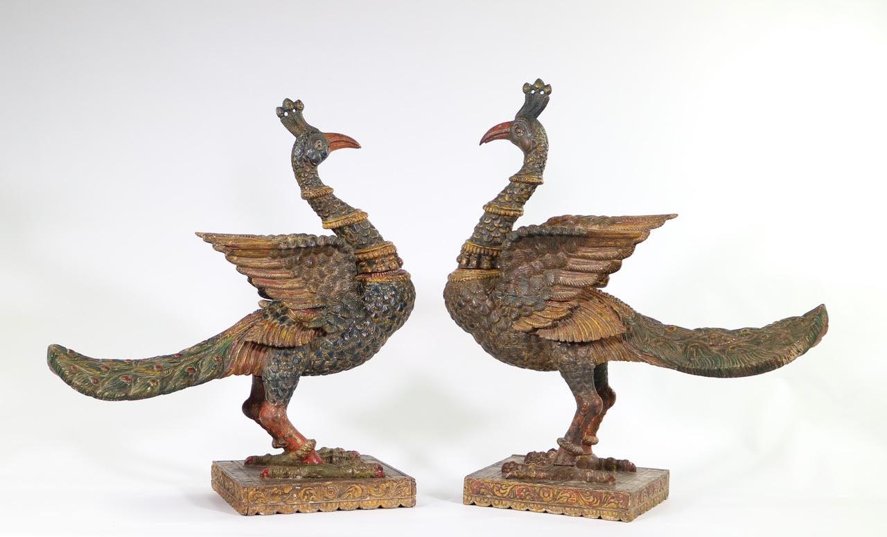 Large pair of antique South Indian poly-chrome wooden peacock sculptures, carved in the late 18th to early 19th century. The pair has exquisitely carved detailing and is mounted on plinths. The life-sized birds are adorned with typical Indian