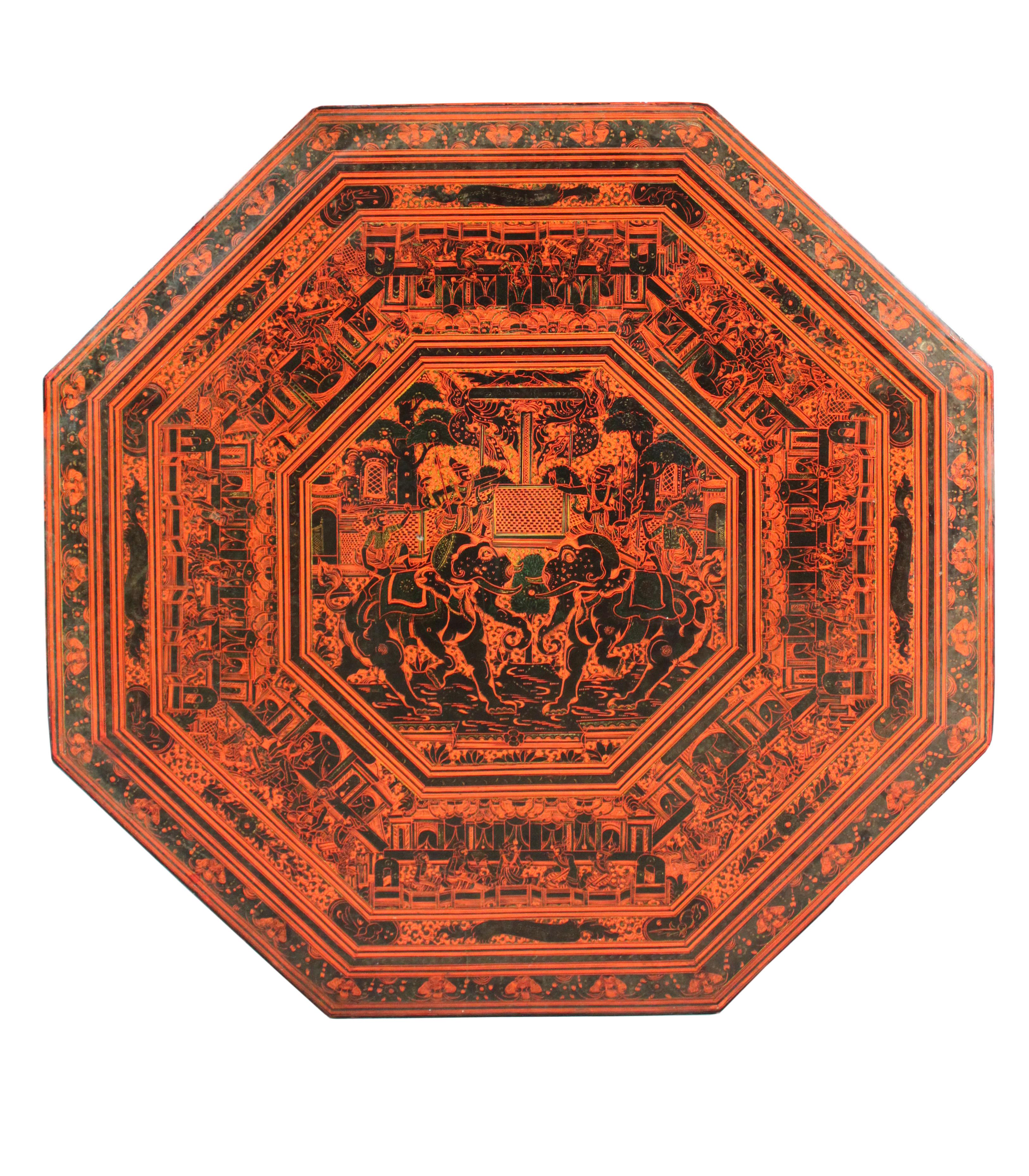 Table en laque rouge indienne de taille inhabituelle ; le plateau octogonal est décoré d'éléphants cabrés entourés d'une frise de personnages et la base présente des détails de lions, d'éléphants et de divers personnages.
Le dessus se retire et la