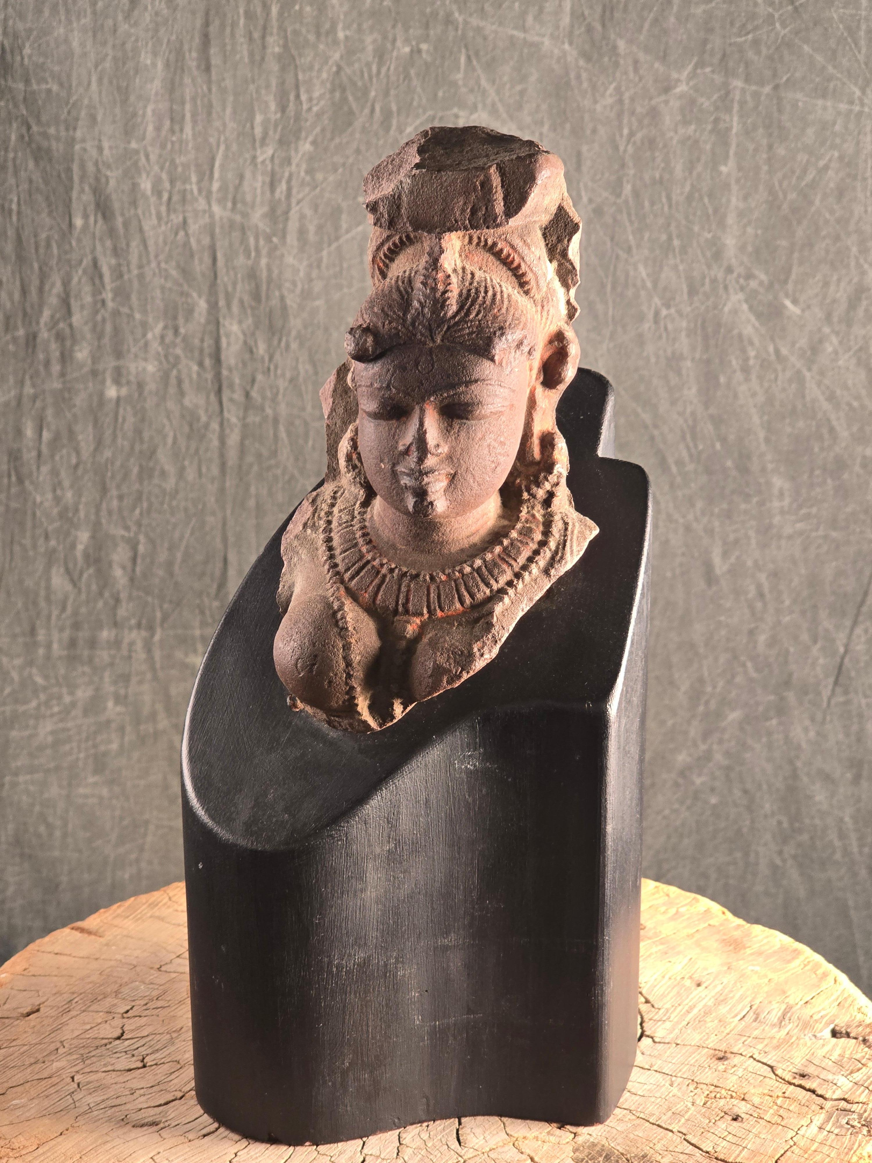 Buste en grès rouge sculpté d'une divinité féminine, Inde, vers le 10e-12e siècle. Le fragment lui-même mesure 8,5 pouces de haut sur 4,5 pouces de large et de profondeur, et mesure 14,5 pouces au total, y compris sa base personnalisée du milieu du