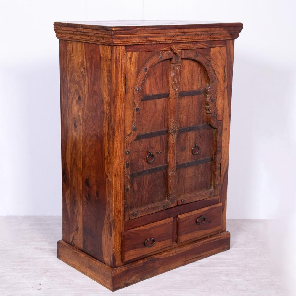 An Indian cabinet made from rosewood and 19th-century window shutter from Bikaner, Rajasthan. The cabinet has a shelved interior and sits on two drawers.
