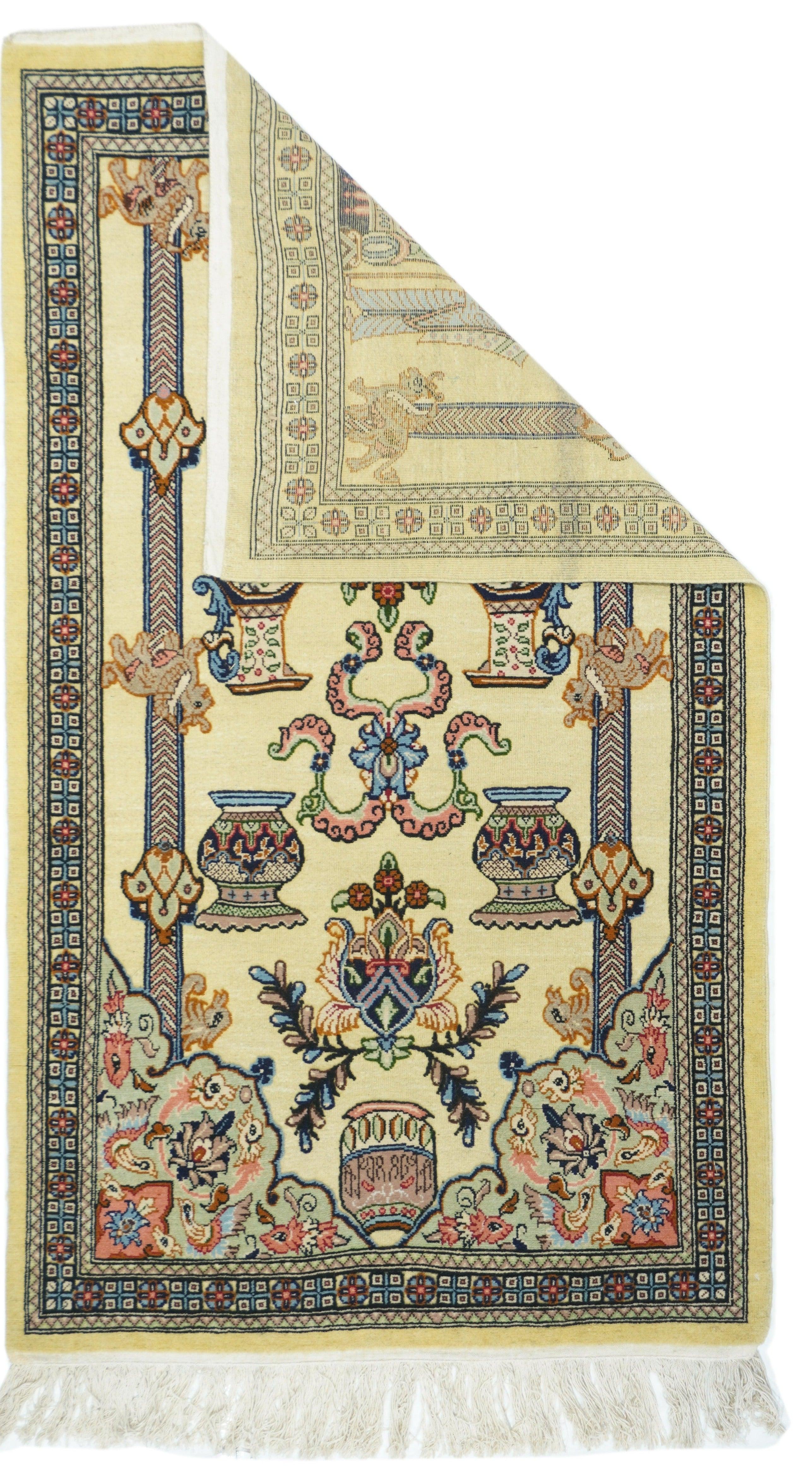 Tappeto indiano 3'4'' x 5'8''. In stile semipittorico con due guerrieri in stile achemenide che sostengono un tabernacolo, al di sopra del quale si trovano vasi, bande di nuvole congiunte, brocche in stile sassanide, una palmetta e un ornamento