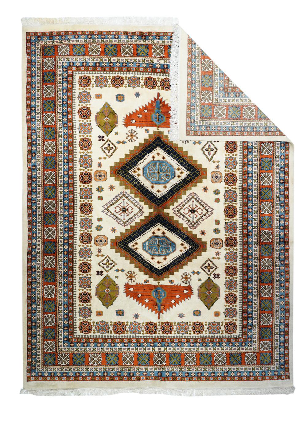 Indianerteppich 8'10'' x 11'9''. Das ecrufarbene Feld zeigt ein kaukasisch inspiriertes Muster aus zwei gemeinsamen, gestuften Rauten in Rot und Ecru mit stark gezackten, abgeflachten Endfünfecken. Sekundäre hakenförmige Rauten und eine implizite
