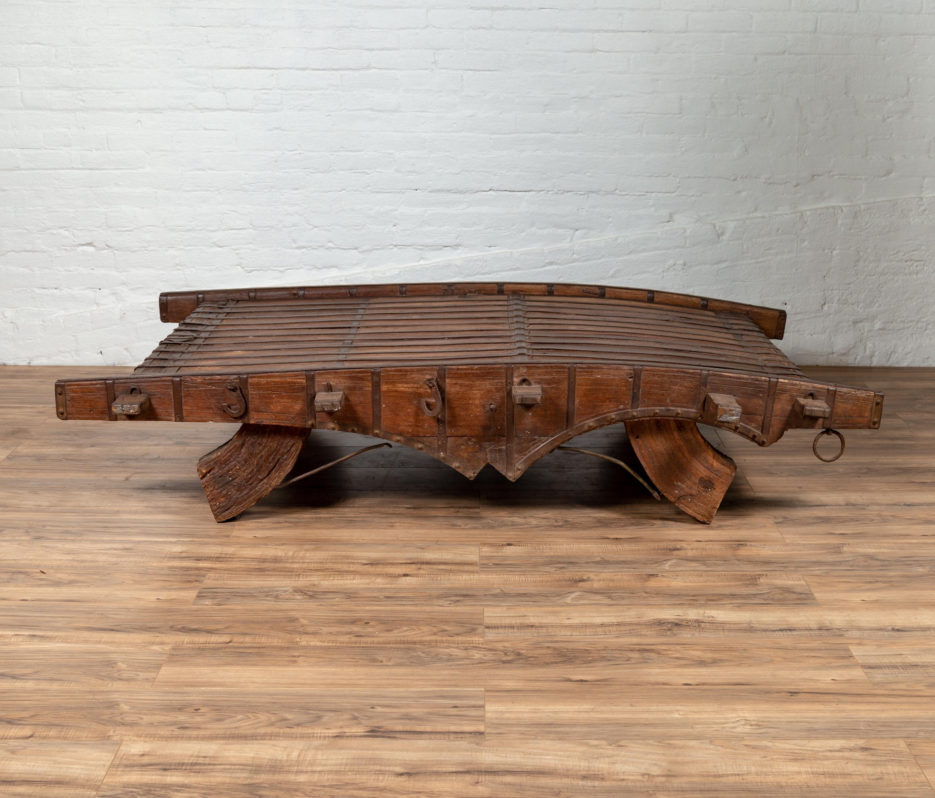 An Indian rustic wooden ox cart from the 19th century, made into a coffee table with convex top and metal accents. We have two tables available, priced and sold individually. Perfect to be used as a coffee table, this conversation piece is an old
