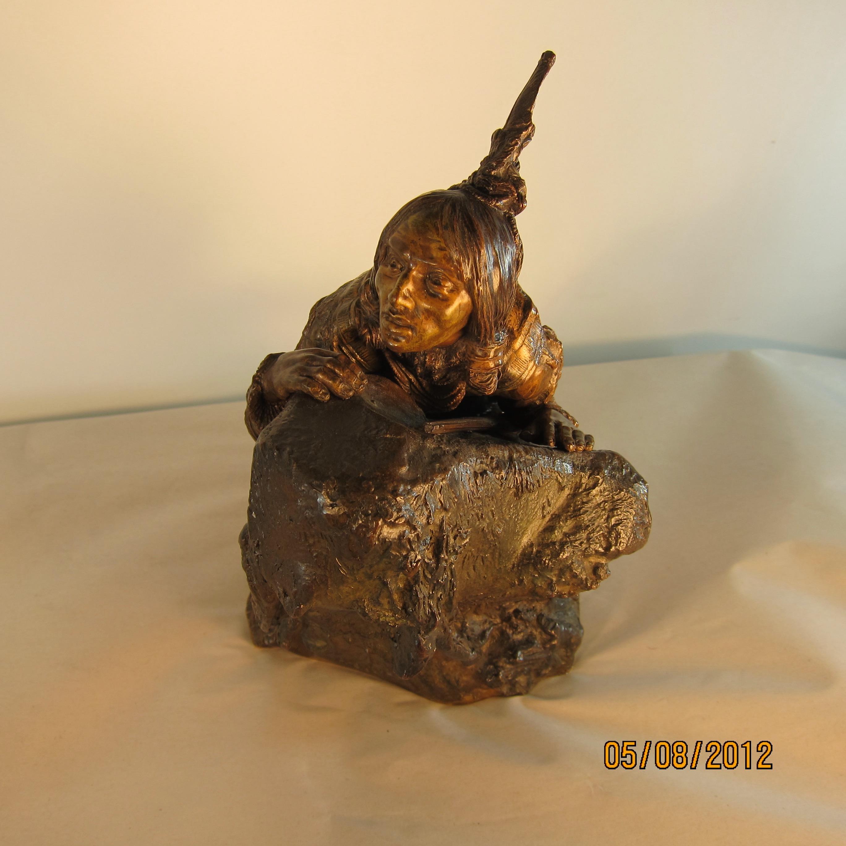 This vintage patinated bronze sculpture is signed Carl Kauba & dates from the early 20th century. It is of an American Indian, wonderfully costumed in a deerskin garment & positioned on a rocky mound scouting his prey. The artist's keen eye for