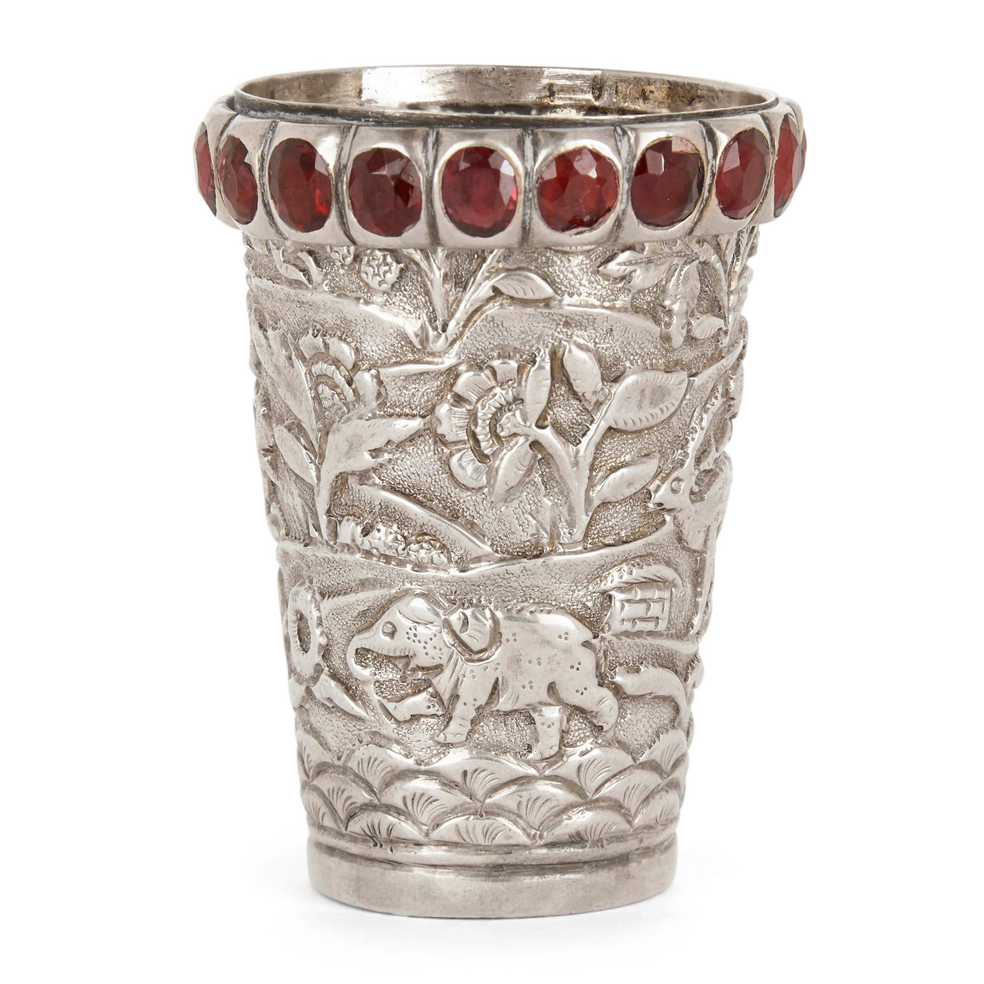 Indischer Silberbecher mit Juwelen und Tieren verziert
Indisch, 19. Jahrhundert
Maße: Höhe 6cm, Durchmesser 4cm

Dieser bezaubernde Becher aus indischem Silber zeichnet sich durch eine wunderschöne, geprägte Oberflächenverzierung aus. Diese