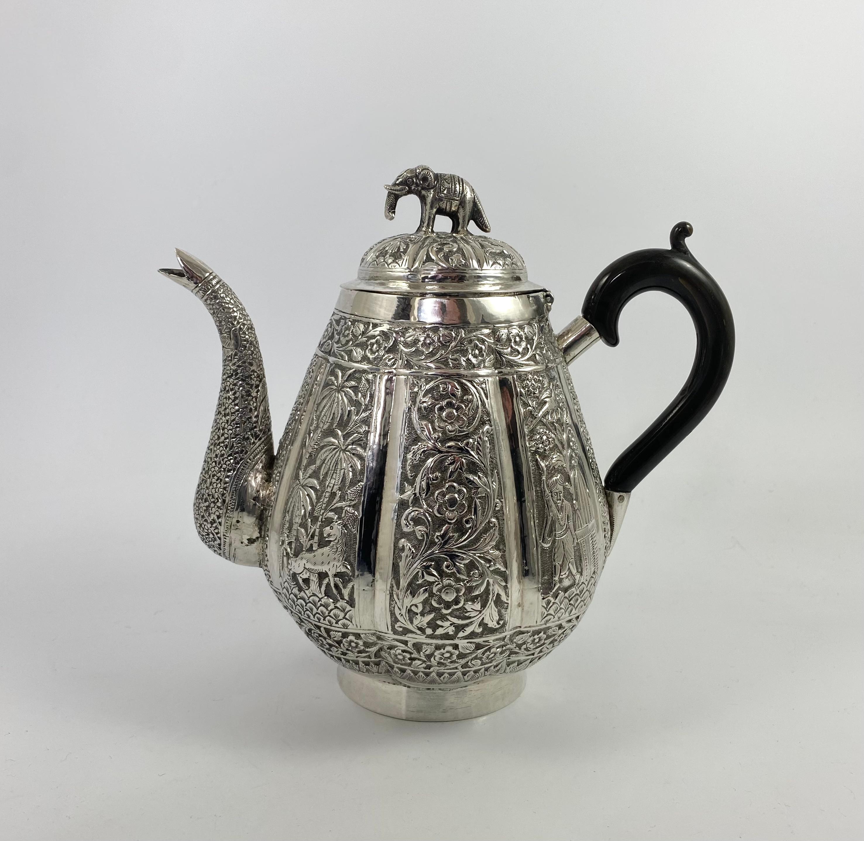 Indian silver three piece teaset, c. 1890. The lobe shaped teapot, chased with panels of flowering plants, figures in villages, and wild animals amongst trees, beneath a continuous panel of floral scrollwork. The spout with birds amongst dense