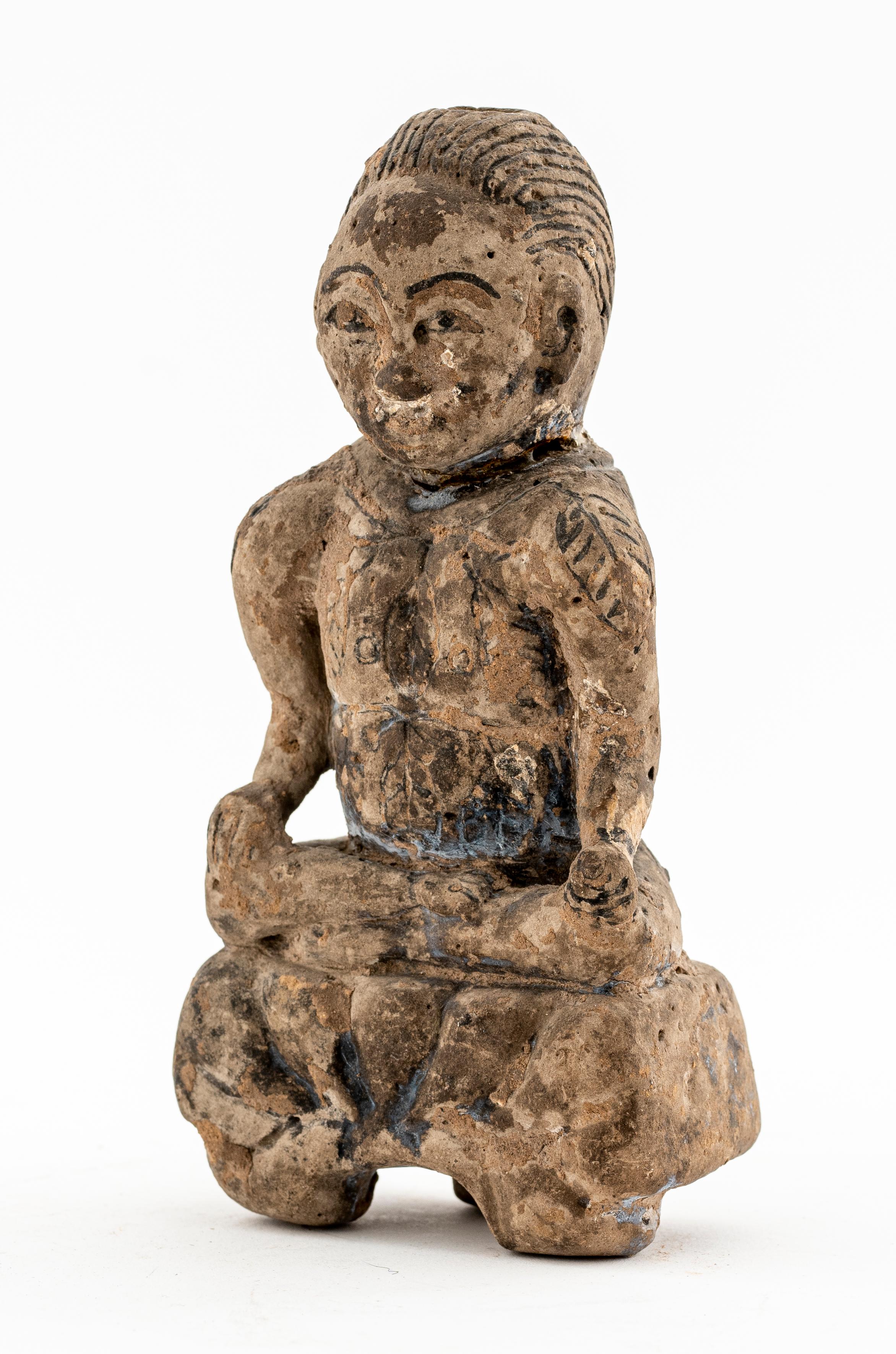 Indian subcontinental terra cotta in the form of a man seated on a tri-footed table- form base and resting his hands on his knees, a rope of leaves slung around his shoulder.
