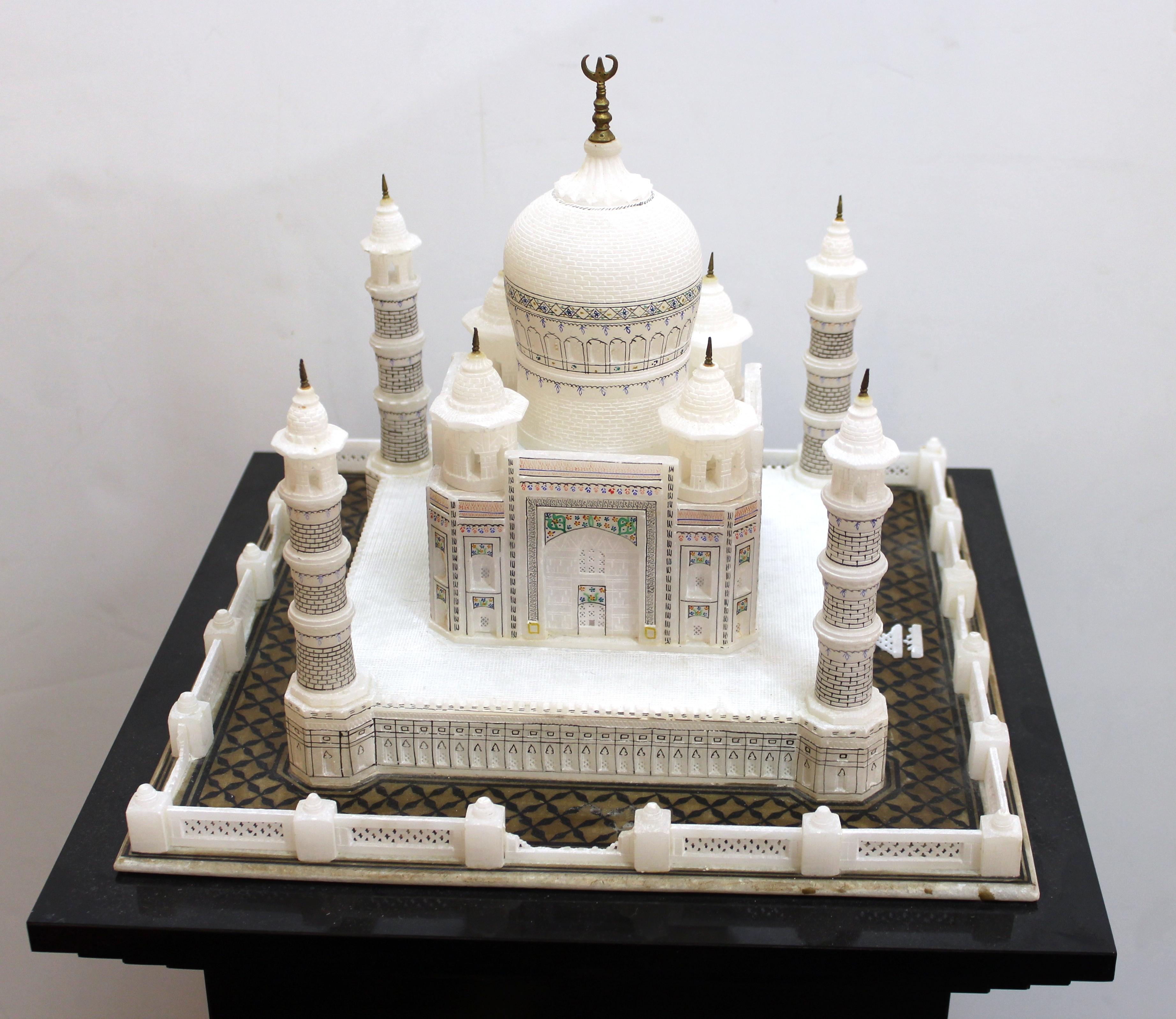 Indian hand-carved and hand-painted architectural scale model of the Taj Mahal, on black composite pedestal. The model is finely detailed and has delicate brass finials on top of the domes. Measures: The model itself is 11
