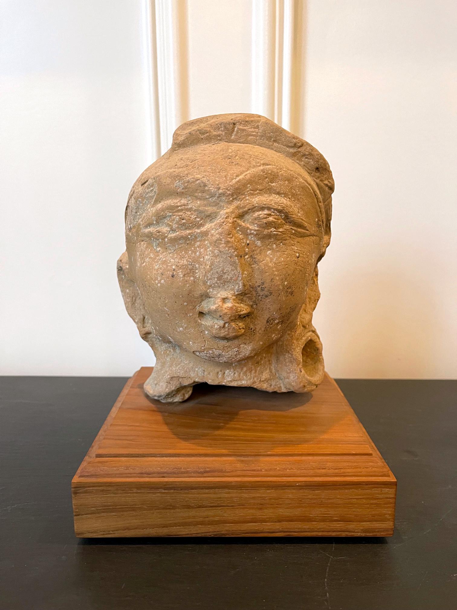 A fragment of Terracotta statue displayed on wood block stand from ancient Indian continent dated to the Gupta period (4th-6th century). The head of the deity was made from molded clay and fired at low temperature and was likely painted when it was