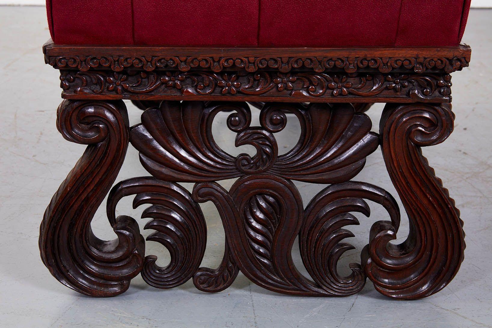 An important Indian Raj ottoman of substantial size with button tufted hand-dyed leather upholstered top on gloriously elaborate hardwood frame with finely carved open fret apron over coiled scroll foliate legs depicting stylized peacocks, Indian,