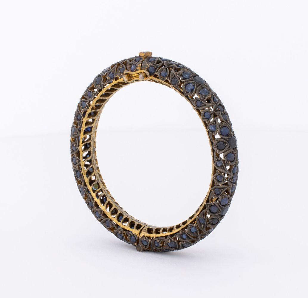 Bracciale a cerniera con zaffiro in argento vermeil indiano, ornato da 96 zaffiri rotondi sfaccettati incastonati per un peso totale di circa 10,40 carati, superfici in argento vermeil e finitura anticata, unite da una chiusura a scatola e linguetta