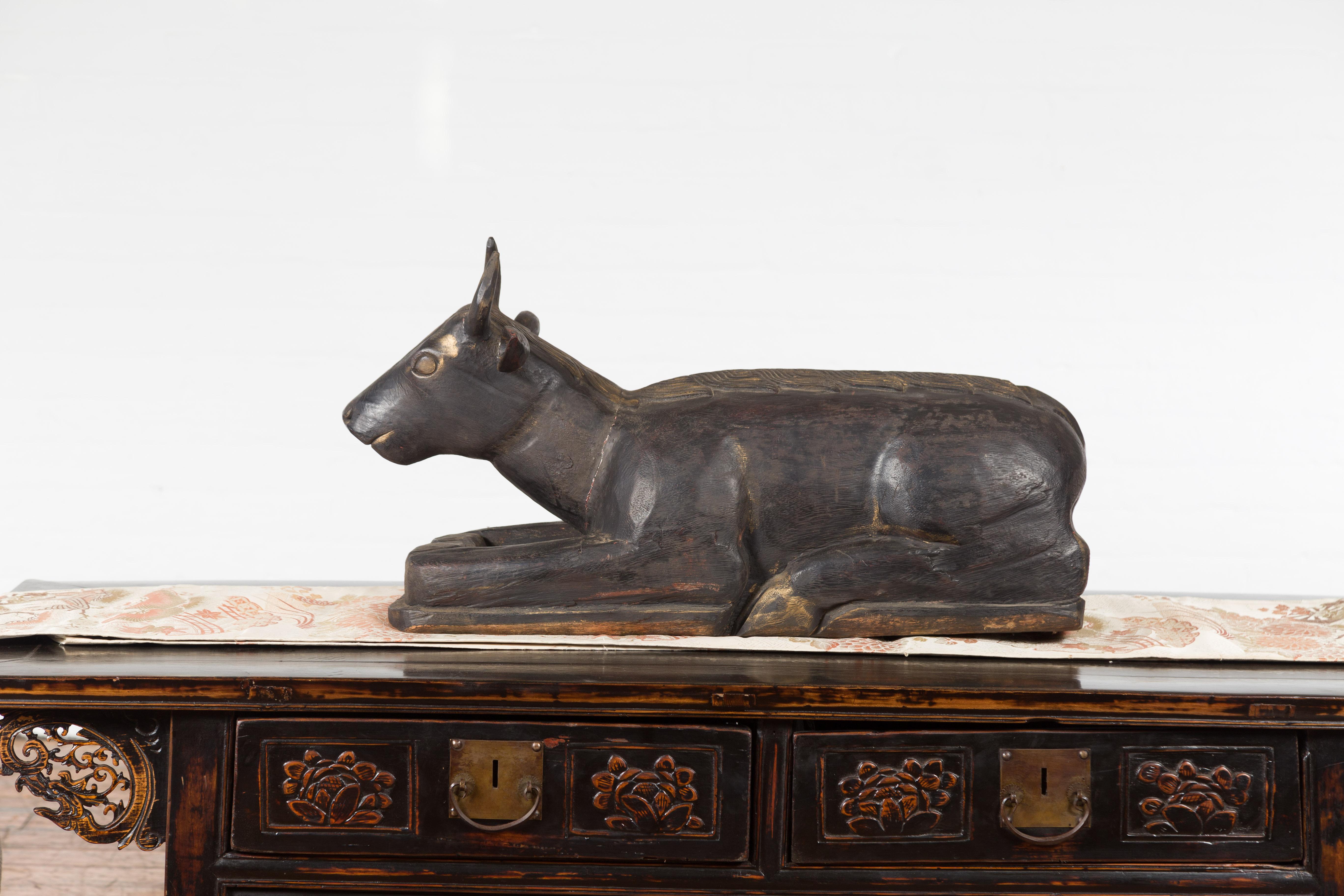 An Indian vintage Nandi bull sculpture from the mid 20th century, with carved motifs and dark patina. Created in India during the mid 20th century, this carved wooden sculpture features Nandi, son of the sage Shilada. Depicted as a bull, Nandi is
