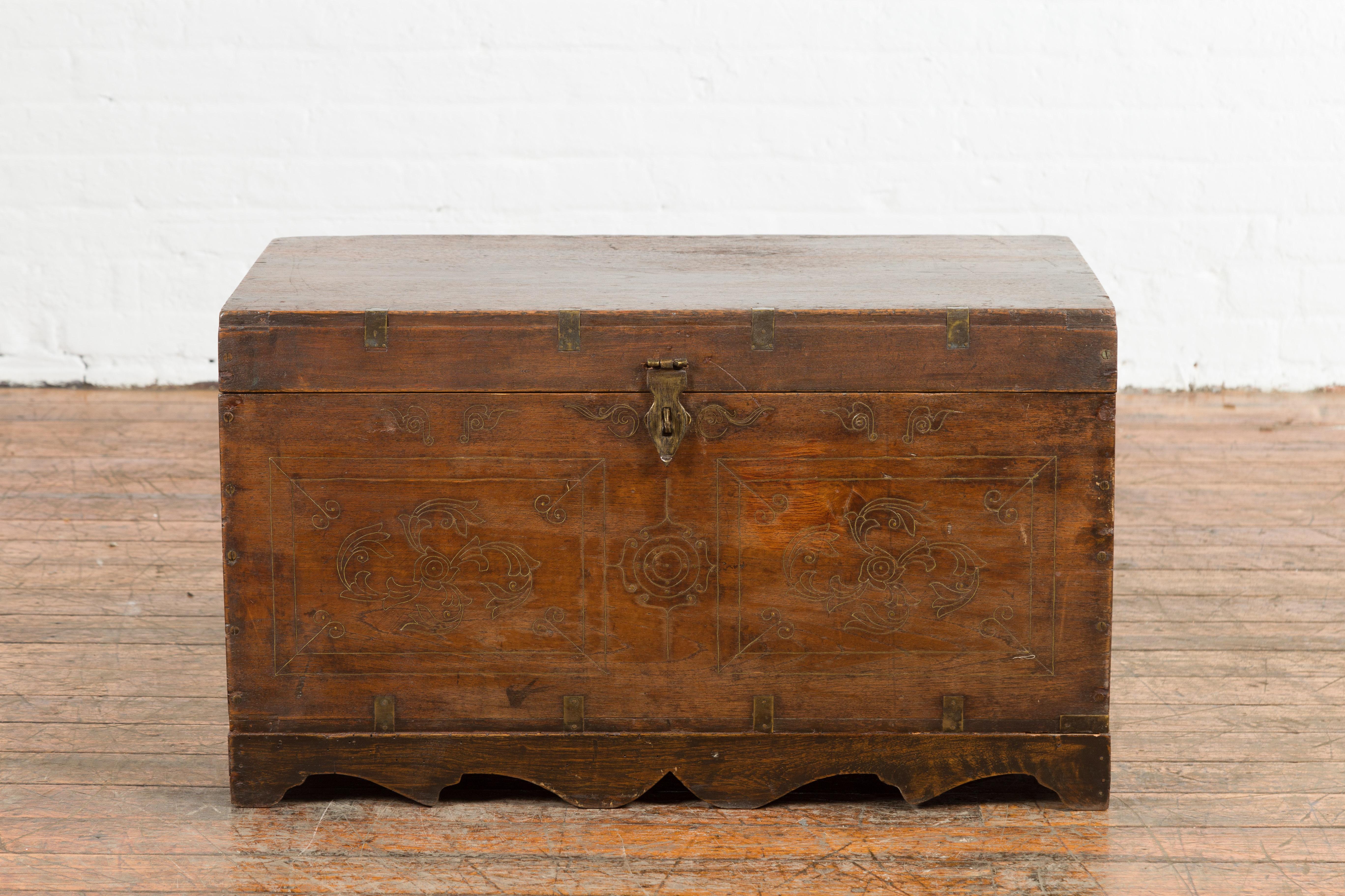 A Indian wedding chest from the mid 20th century, with brass accents, multiple jewelry compartments, floral décor and petite central mirror. Created in India during the midcentury period, this wooden wedding chest is adorned with an inlaid brass