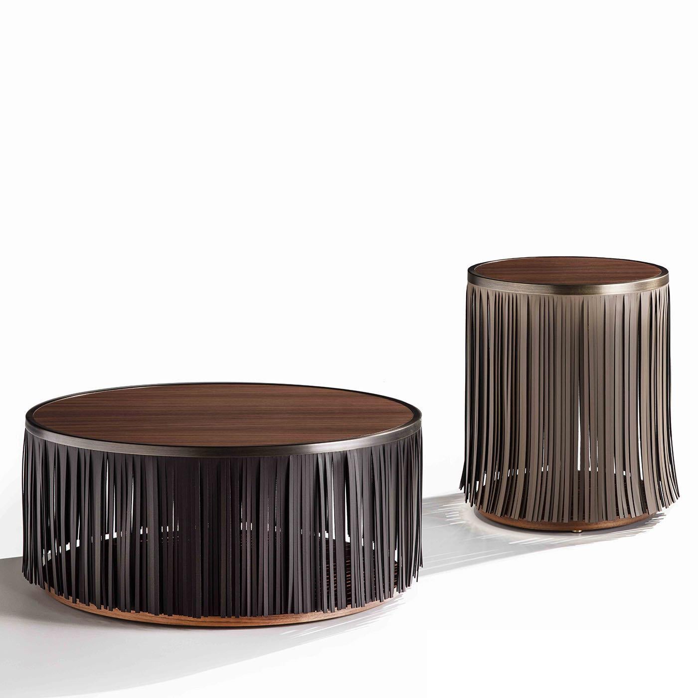 Modern and unique, the Indian Coffee Table is a striking centerpiece that will create a statement in any home. Boasting a simple round shape with a Canaletto walnut wood top and base, this table showcases an eye-catching fringe of black leather