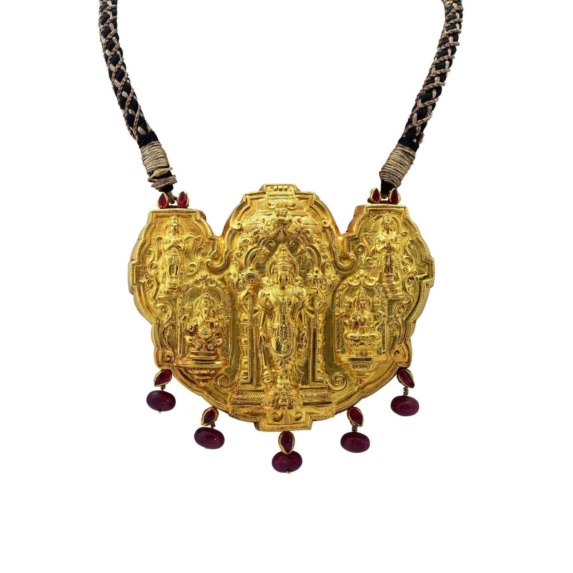 This gorgeous wedding Indian Temple necklace features images of Hindu Deities crafted in 22K Yellow Gold, telling a story rich in symbolism. The medallion measures 4.27 inches long and 3.45 inches high. It hangs off a black and gold tassel cord. 