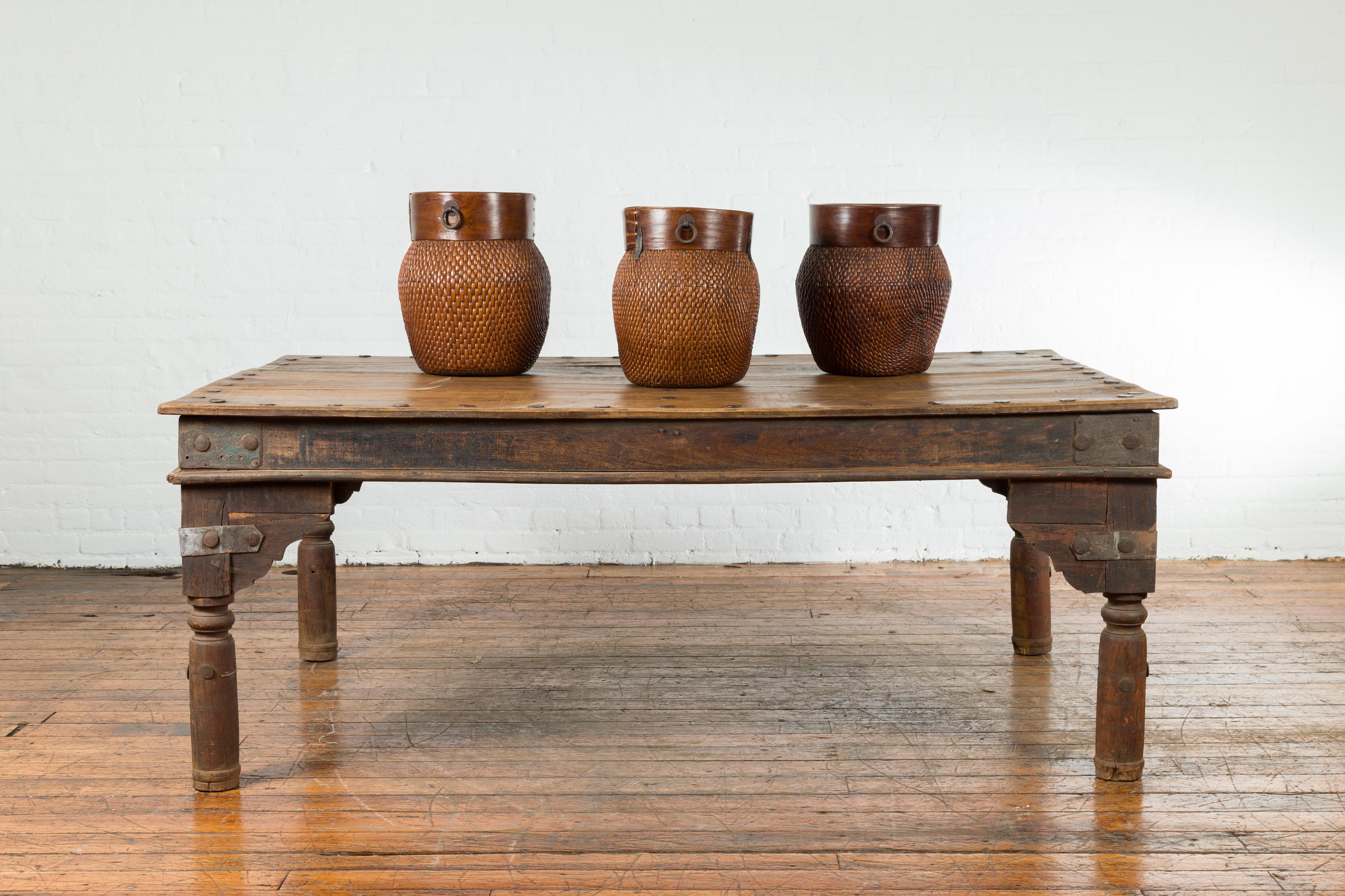 An Indian wooden dining table from the early 20th century with iron studs, metal braces and baluster legs. The height can be customized. Created in India during the early years of the 20th century, this dining table features a rectangular planked