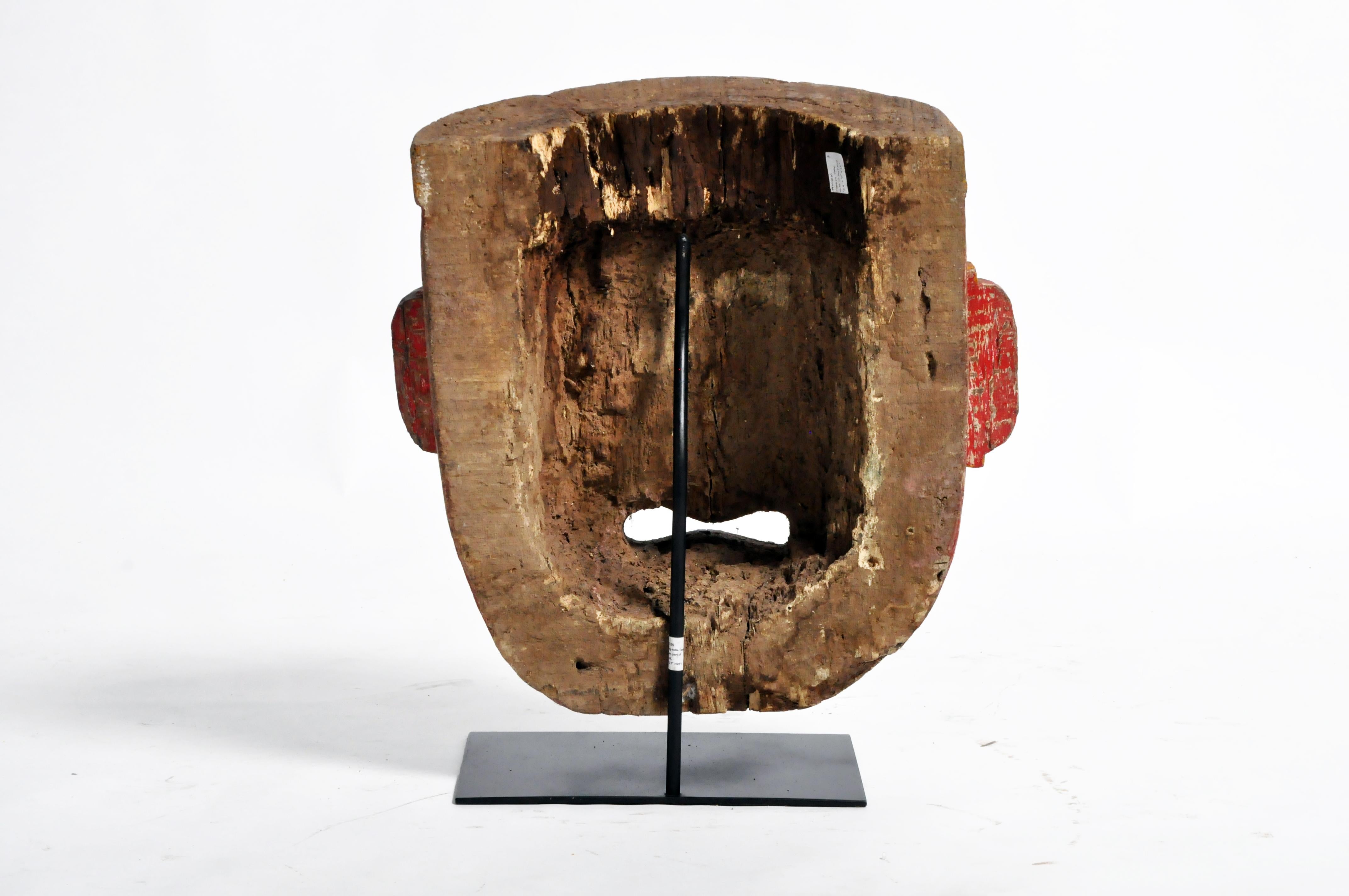 Poly-chrome wooden mask from Rajasthan, India, made from Sheesham wood, circa 20th century. The mask features a grotesque smile that is designed to ward off the evil eye. According to traditional beliefs, a beautiful mask would only lure envy and