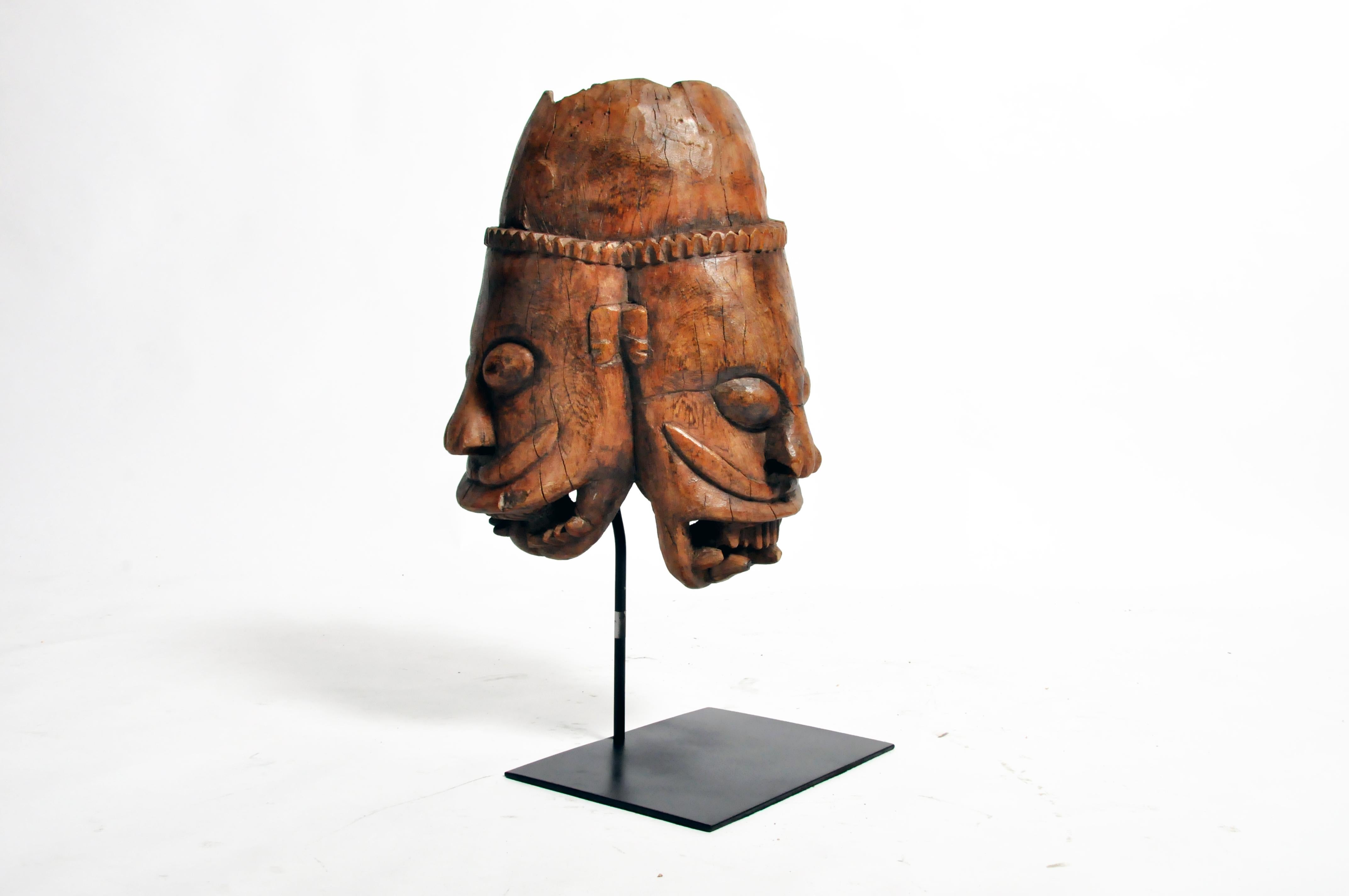 Poly-chrome wooden mask from Rajasthan, India, made from Sheesham wood, circa 20th century. The mask features a grotesque smile that is designed to ward off the evil eye. According to traditional beliefs, a beautiful mask would only lure envy and