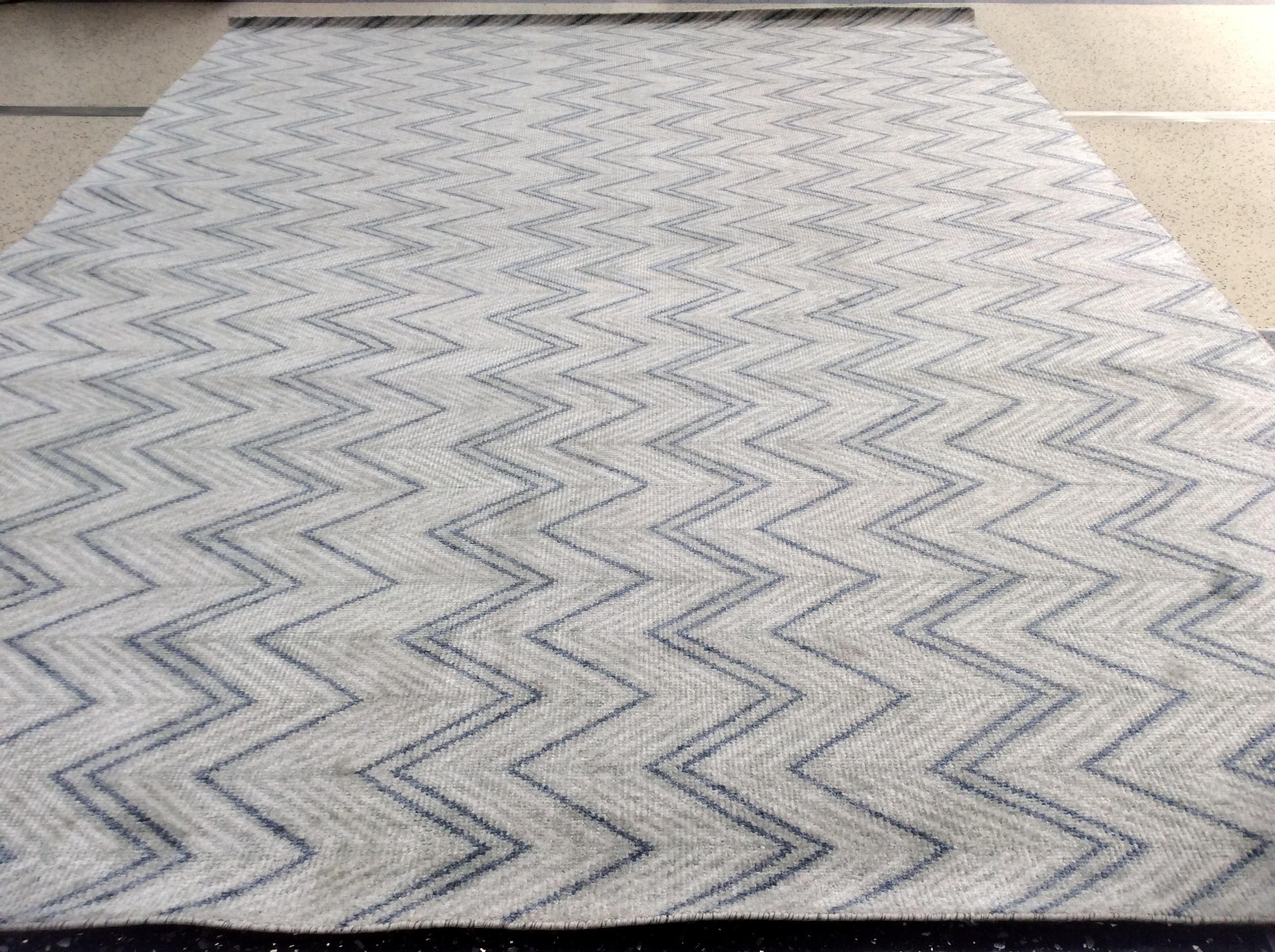 Light and dark lines zig and zag their way across this vibrant Indian area rug.  Blue, sage and eggshell alternate to enliven a space without overwhelming it. Hand knotted in India.