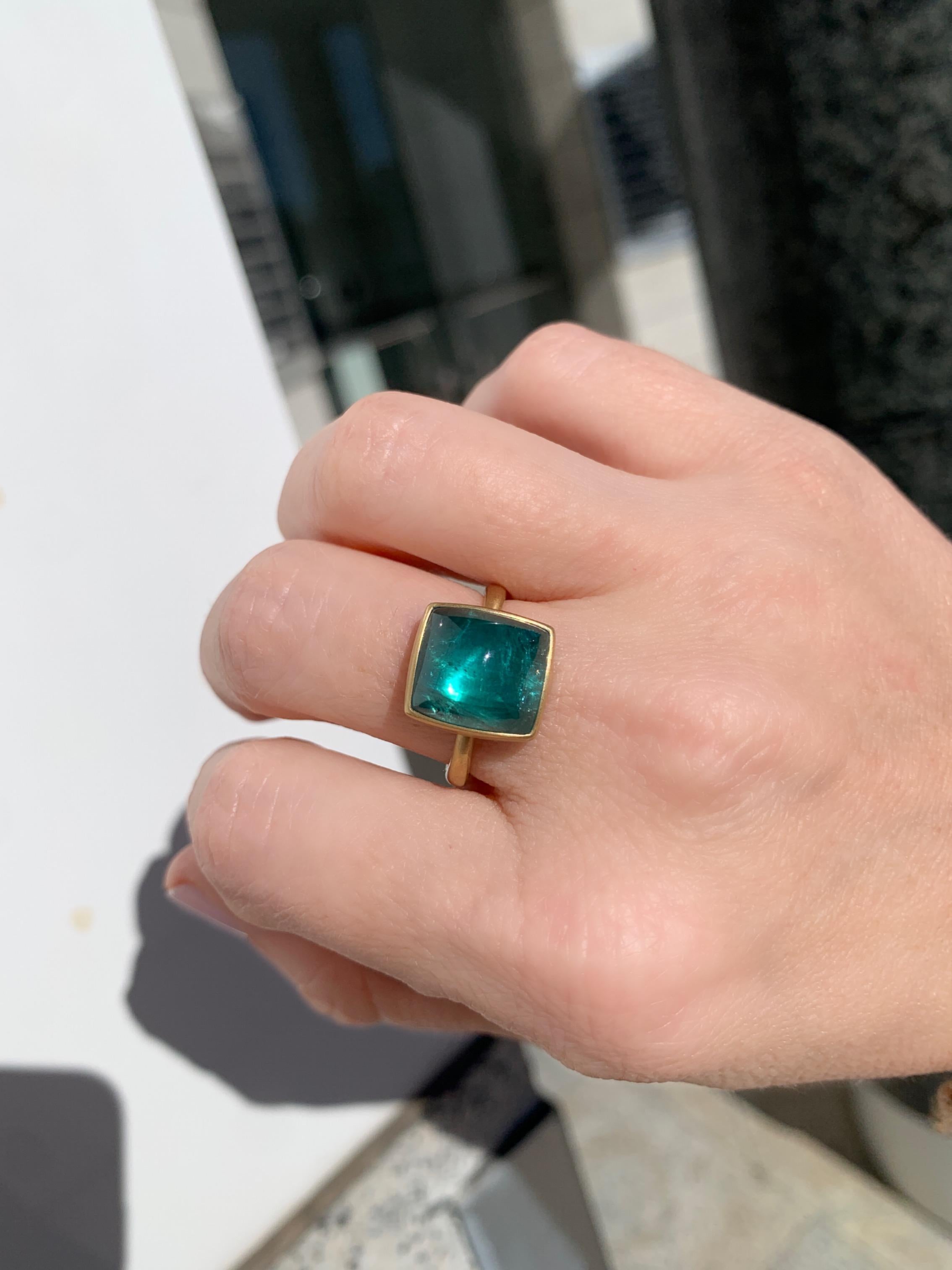 One of a kind ring hand-fabricated by acclaimed jewelry maker Lola Brooks in the artist's signature-finished 18k yellow gold featuring a magical, glowing 9.29 carat greenish-blue indicolite tourmaline cushion cabochon on a tapered 18k yellow gold