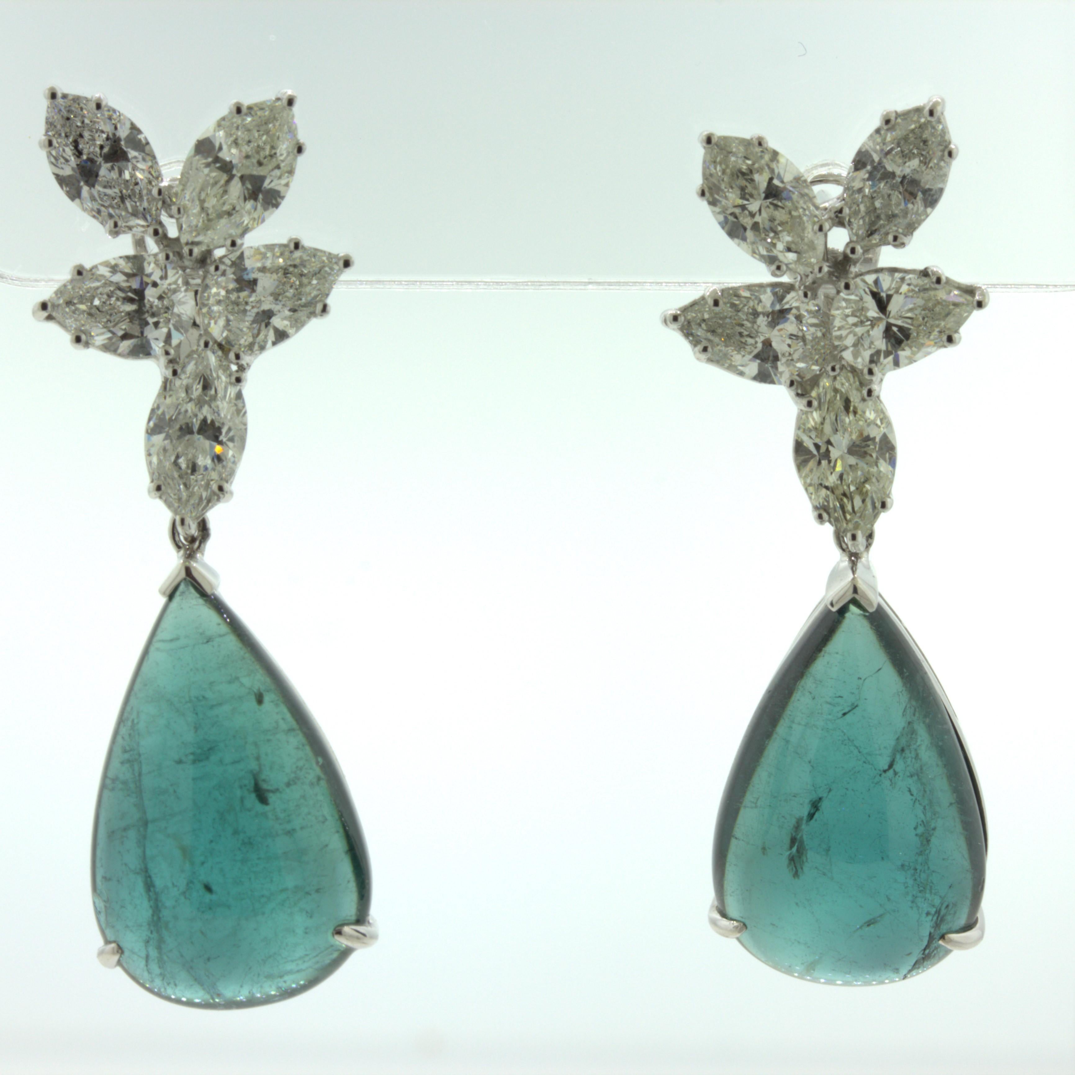 An elegant pair of drop earrings featuring 2 pear-shape cabochon indicolite tourmaline weighing 25.60 carats total. They have a rich blue-green color and are perfectly matching in size, shape and color. They are accented by clusters of very large