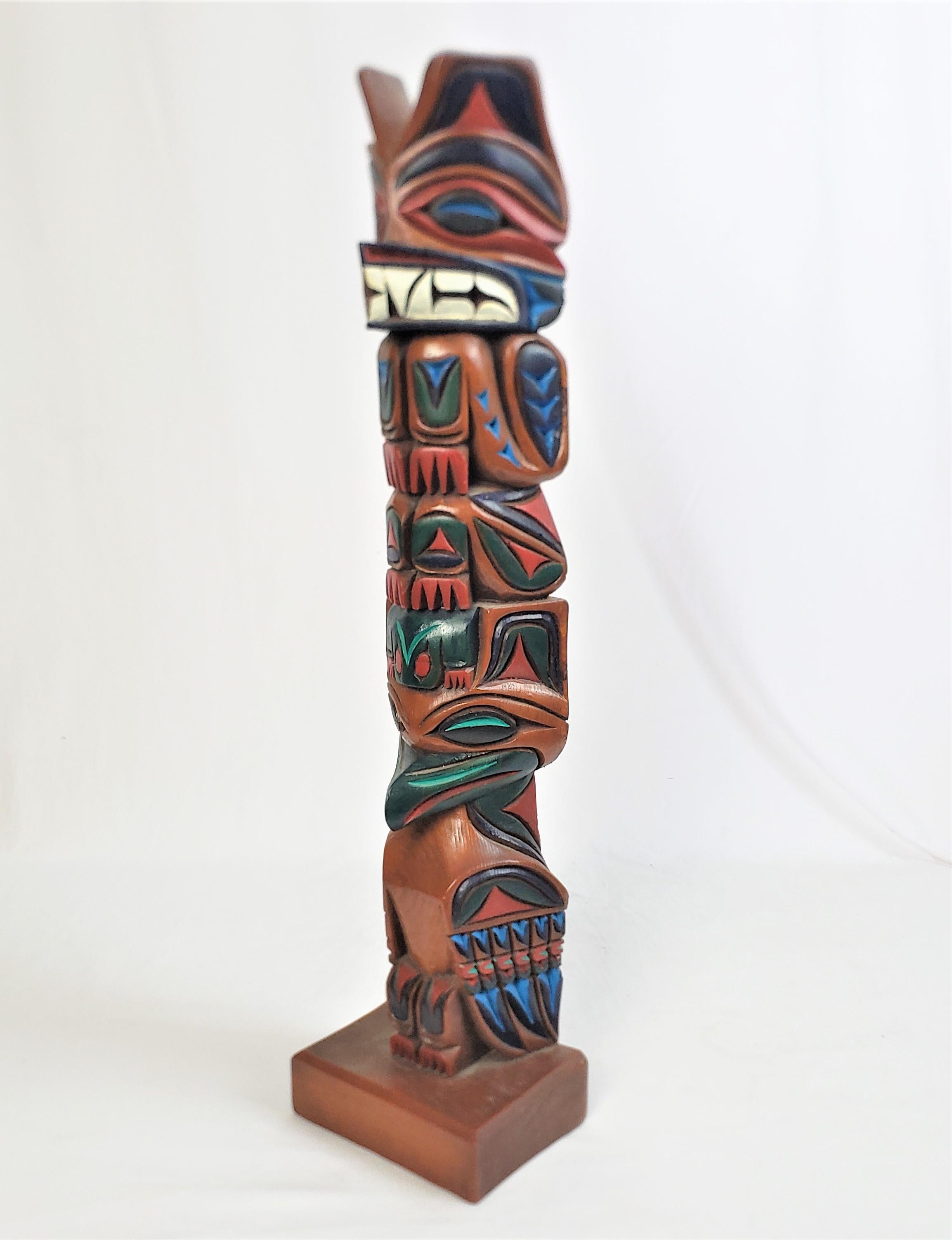 This folk art carved and polychrome painted totem pole is signed by an unknown artist and originated from the United States and dates to 1985 and done in a West Coast Haida style. The totem is composed of cedar and is hand-carved with stylized