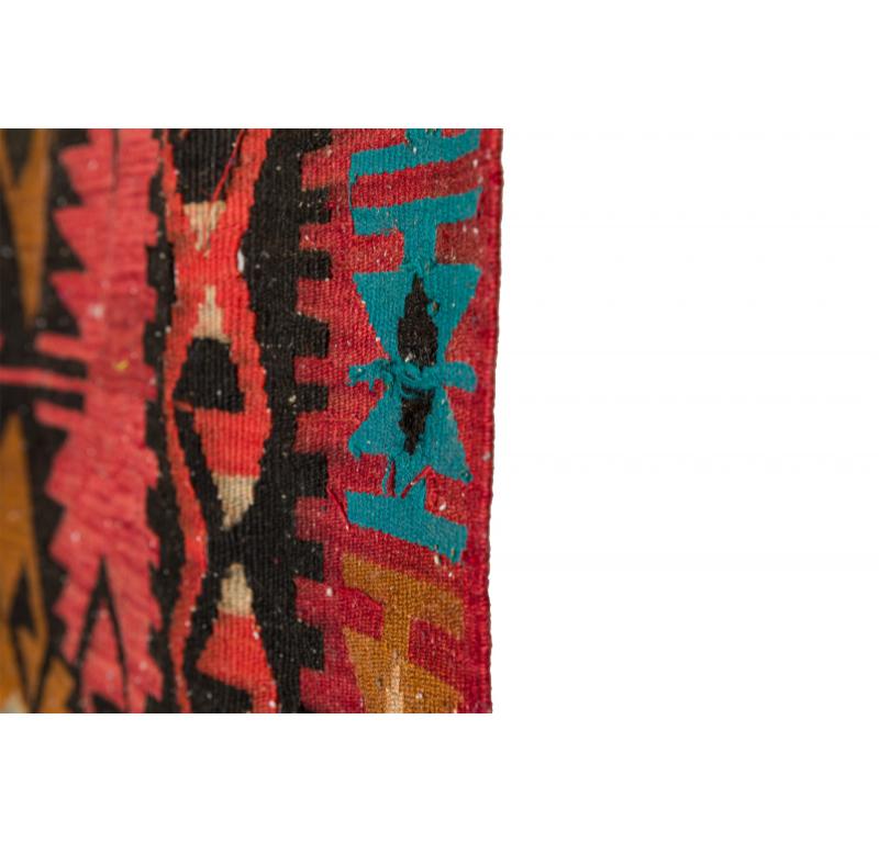 Indigenous American (possibly Navajo) woven rectangular floor runner rug with a geometric pattern in shades of red, pink, brown, blue, white, and gray with white fringe on the two shorter ends.

Condition: Good; Wear consistent with age and use