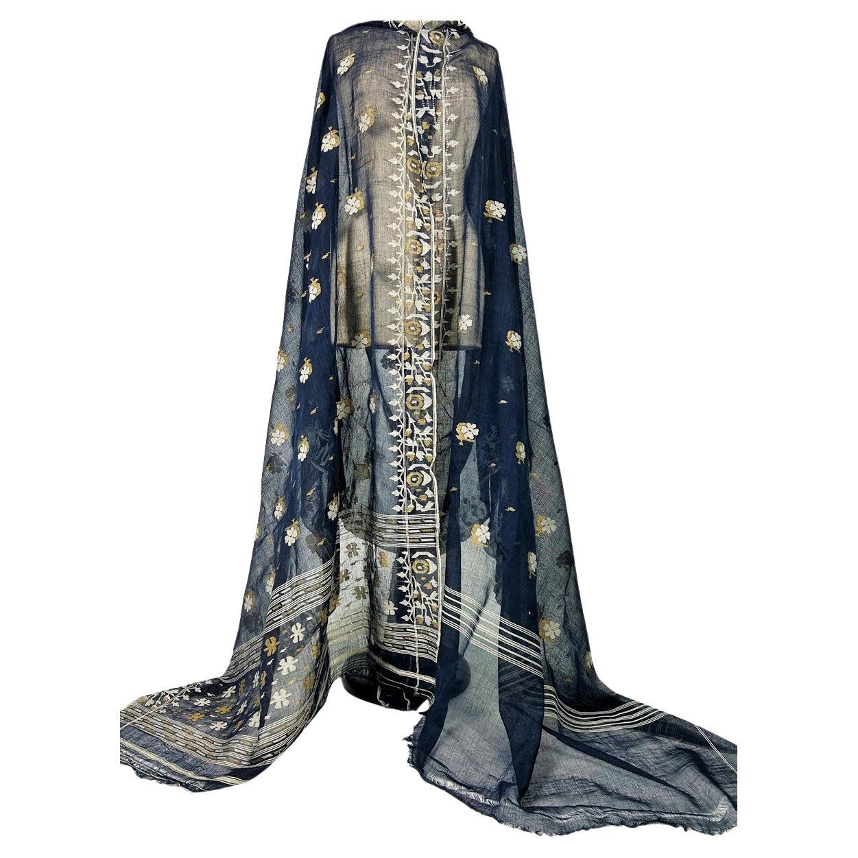 Circa 1930-1950
Bengala India

Un sari indiano trasparente in cotone broccato del Bengala chiamato Jamdani, lungo 453 cm per 110 cm di larghezza! Voile di cotone tinto indaco ricamato con motivi geometrici di ispirazione Mughal in bianco e oro. Il