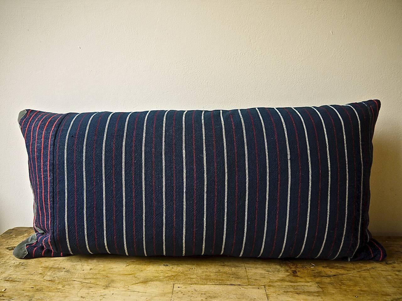 French 19th century woven cotton and wool striped cushion of dark indigo with white, red colors. Original piece made up of two different stripes with an 'as found ' border of a French 19th century grey cotton trim at the base and to the side of the