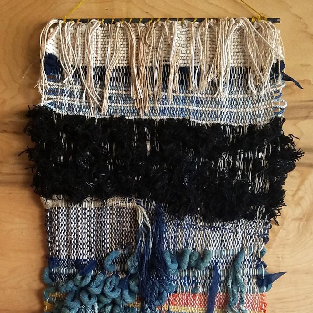 Handwoven wall hanging by Janelle Pietrzak of All Roads. Shades of indigo, navy blue, cream and black. This piece is multiple woven panels hand-stitched together to make one piece. 

Fibers used are cotton, linen and wool Weaving hangs from a steel