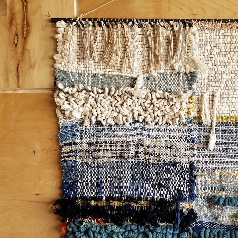 Handwoven wall hanging by Janelle Pietrzak of All Roads. Shades of indigo, navy blue, cream and black. This piece is multiple woven panels hand stitched together to make one piece. 

Fibers used are cotton, linen and wool Weaving hangs from a steel