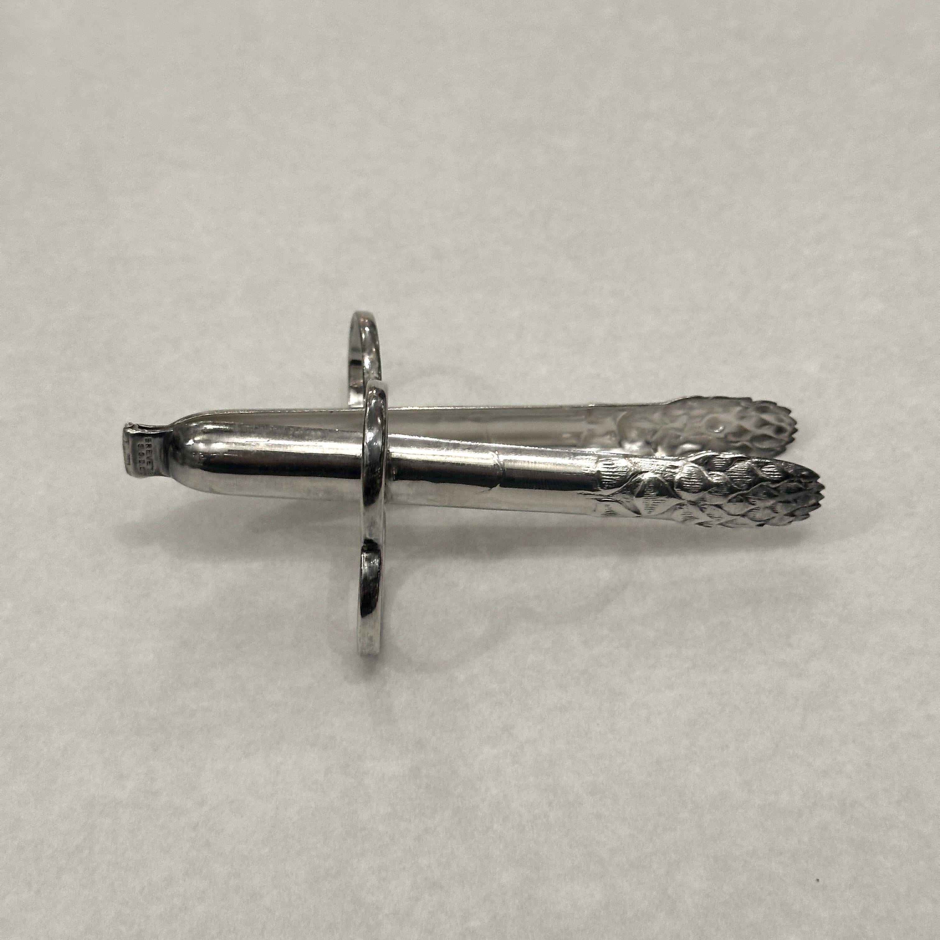 An elegant individual asparagus tongs crafted by the prestigious Christofle, a true emblem of French refinement. This piece perfectly combines beauty and functionality, made of silver-plated metal and adorned with a delicate raised motif of