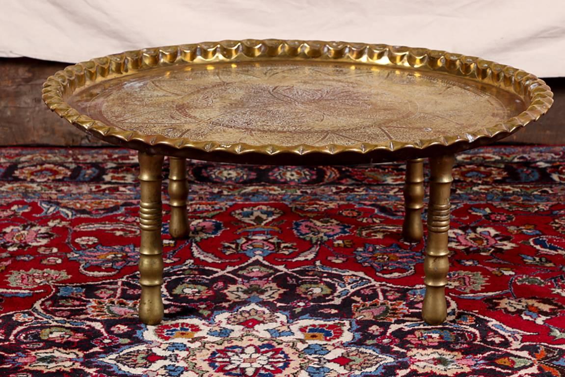 Indo-Persian table, elaborately engraved round floral interlaced patterned brass top with a pinched rim, raised in one piece on four turned brass legs.

Condition: Expected wear and signs of use including some surface scratching and nicking along