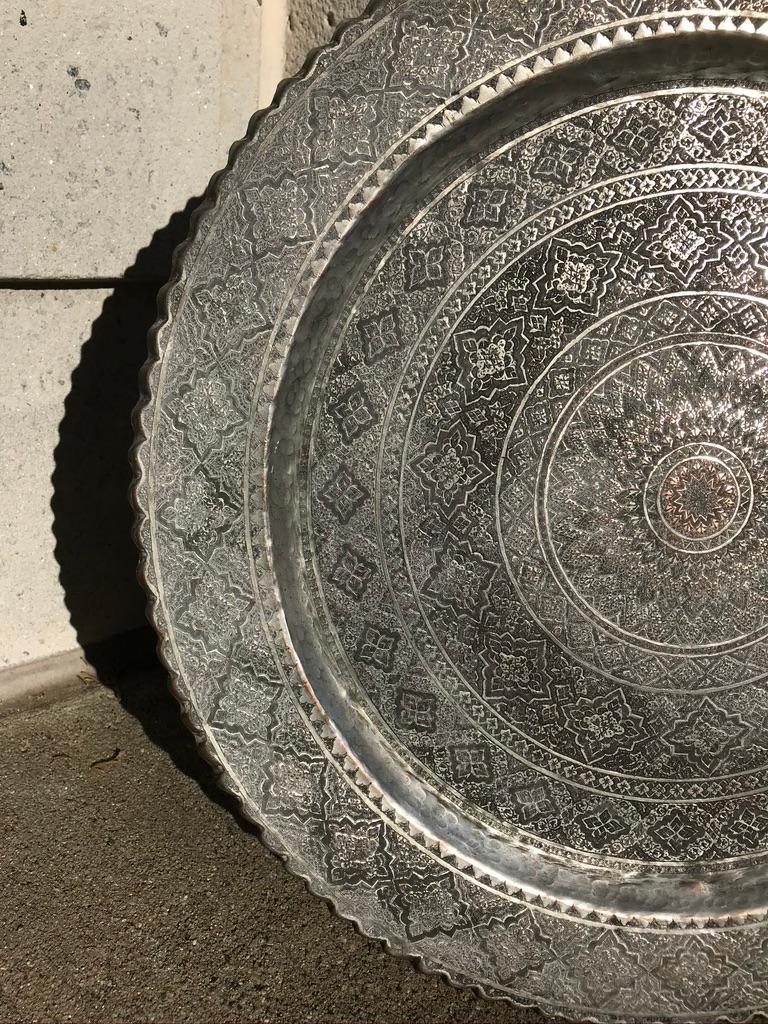 A copper charger with tinned surface covered in etched geometric, floral Persian decorations. A handsome decorative centerpiece or wall hanging. Beautiful handmade craftsmanship.