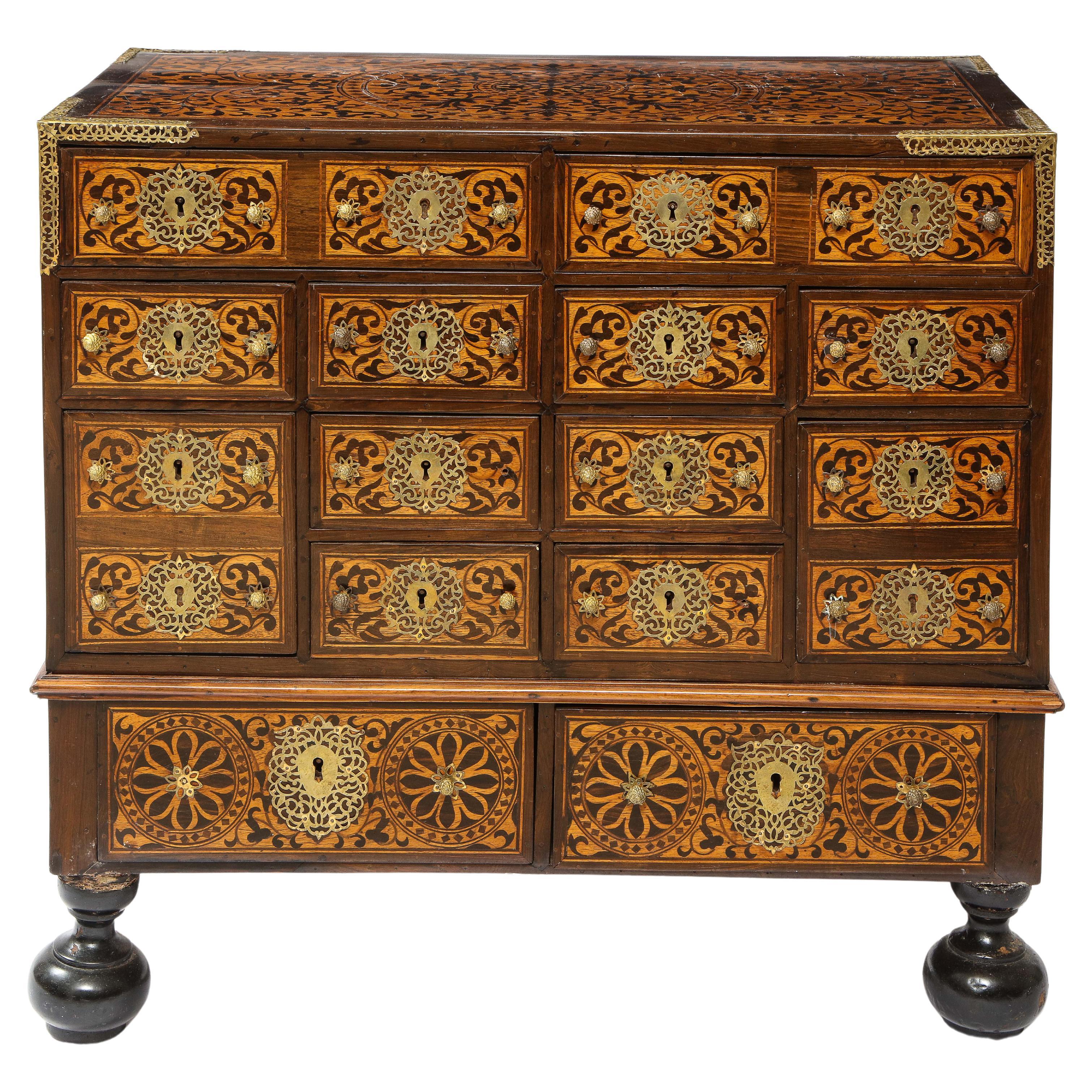 An Indo- Portuguese brass-mounted hardwood and Indian Wood marquetry cabinet, Goa. Gorgeously made with hand-cut hardwood and the finest quality of other Indian veneered wood in two separate parts. Fitted with twelve drawers and resting on bun feet.